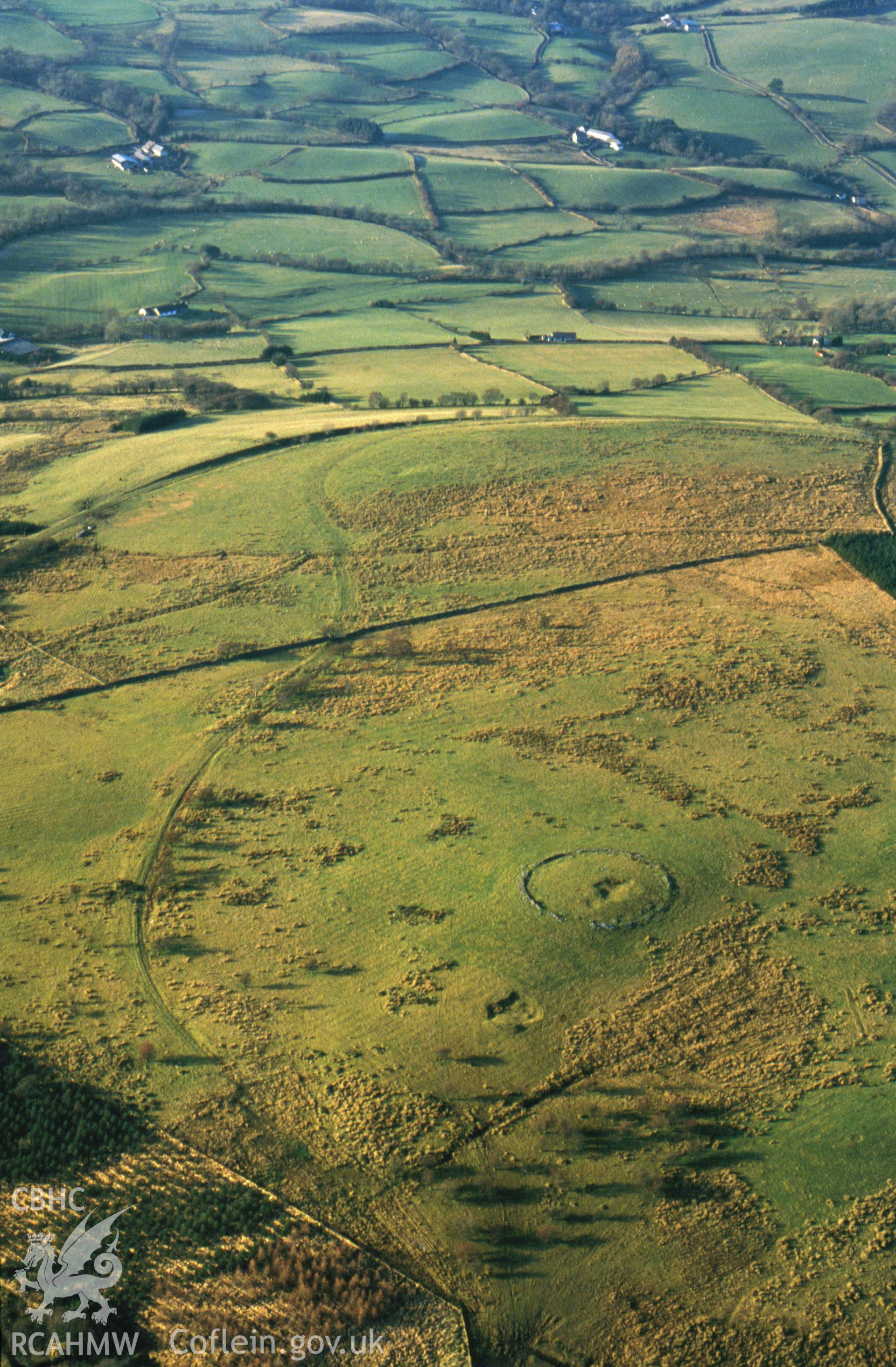 RCAHMW colour slide oblique aerial photograph of enclosure north of Cnewr, Cray, taken by CR Musson on 24/11/88. The image also shows the route of the Brecon Forest Tramroad..