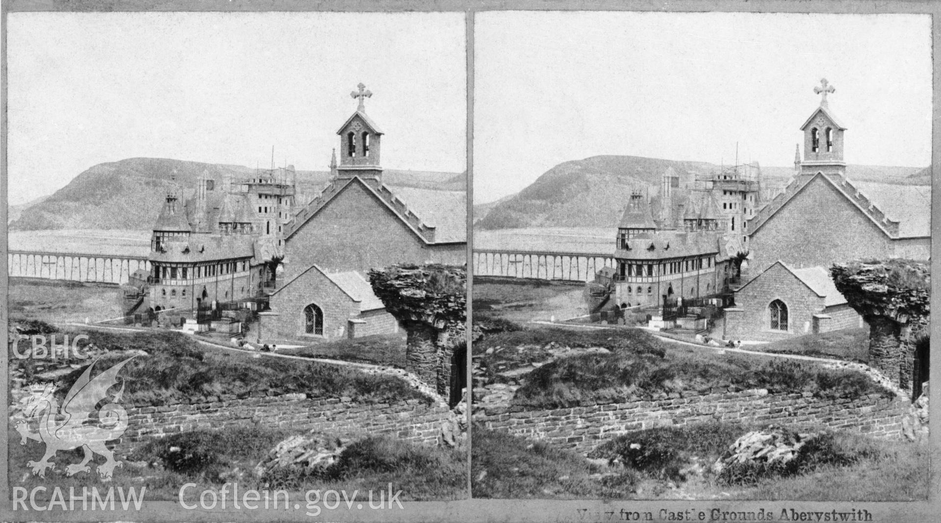 Black and white print of steroscopic photograph of the Old College, University College of Wales, viewed from Aberystwyth Castle grounds. The towers of the north wing are under construction, probably during J.P.Seddon's continuing work on the college prior to the fire of 1885.