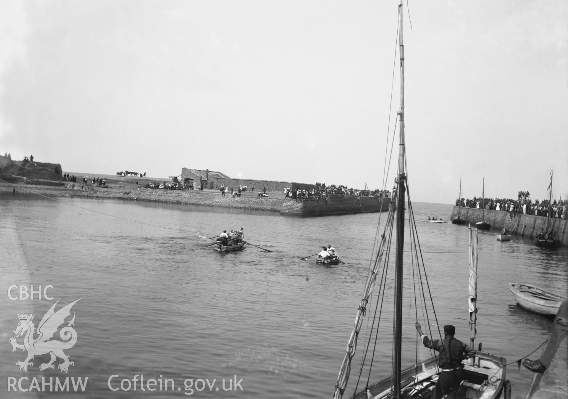 Black and white image dating from c.1910 showing the harbour in Aberaeron with a boat race in progress.