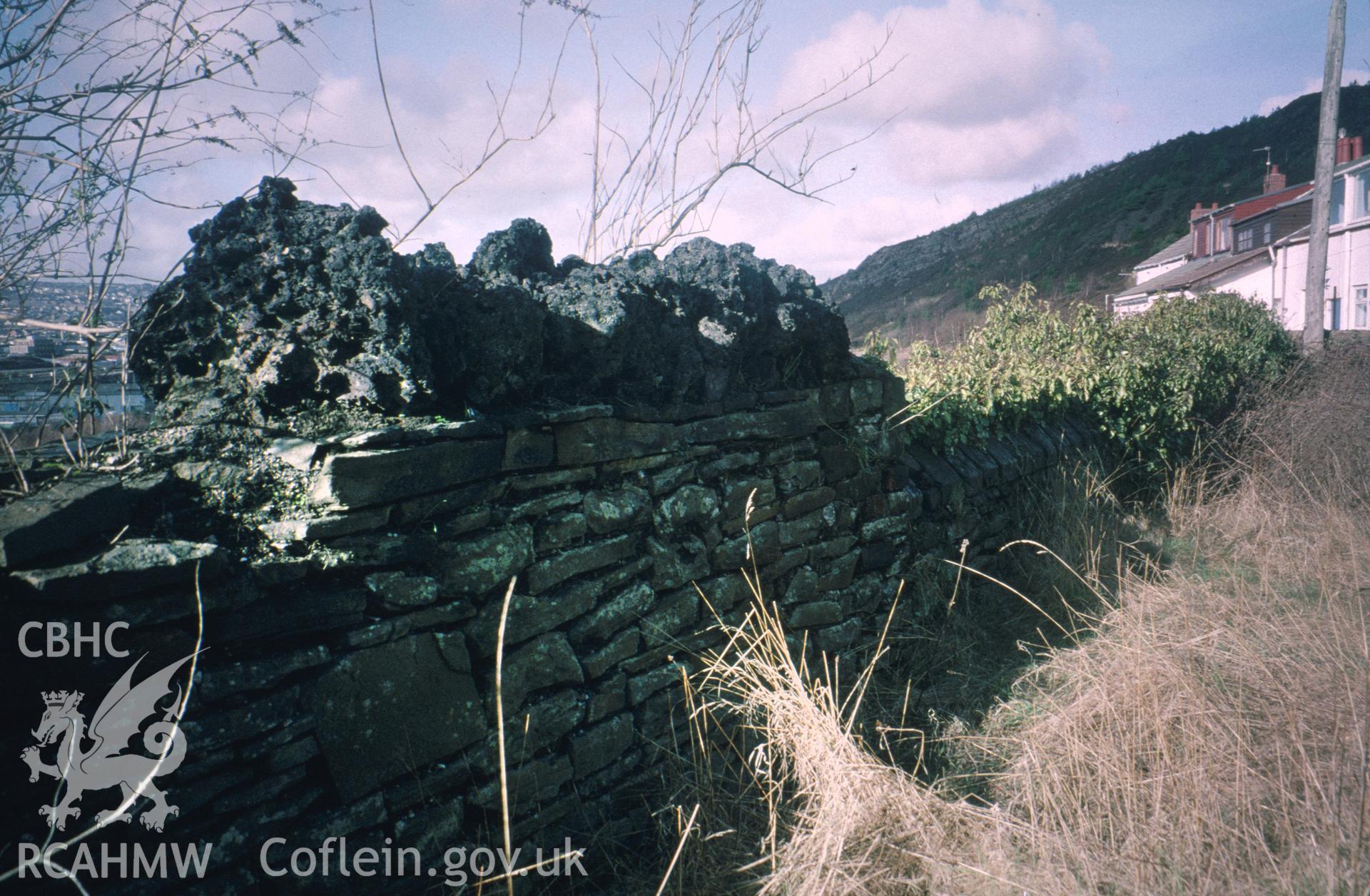 Colour slide of All Saints, Kilvey Road, Swansea: showing rough copper-slag coping on the west churchyard wall.