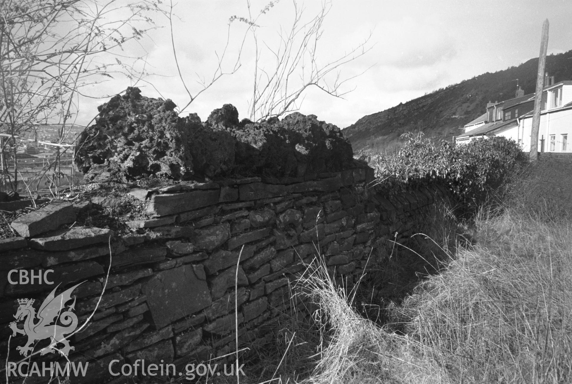 Photograph of All Saints Church, Kilvey Road, Swansea: showing rough copper-slag coping on the west churchyard wall.
