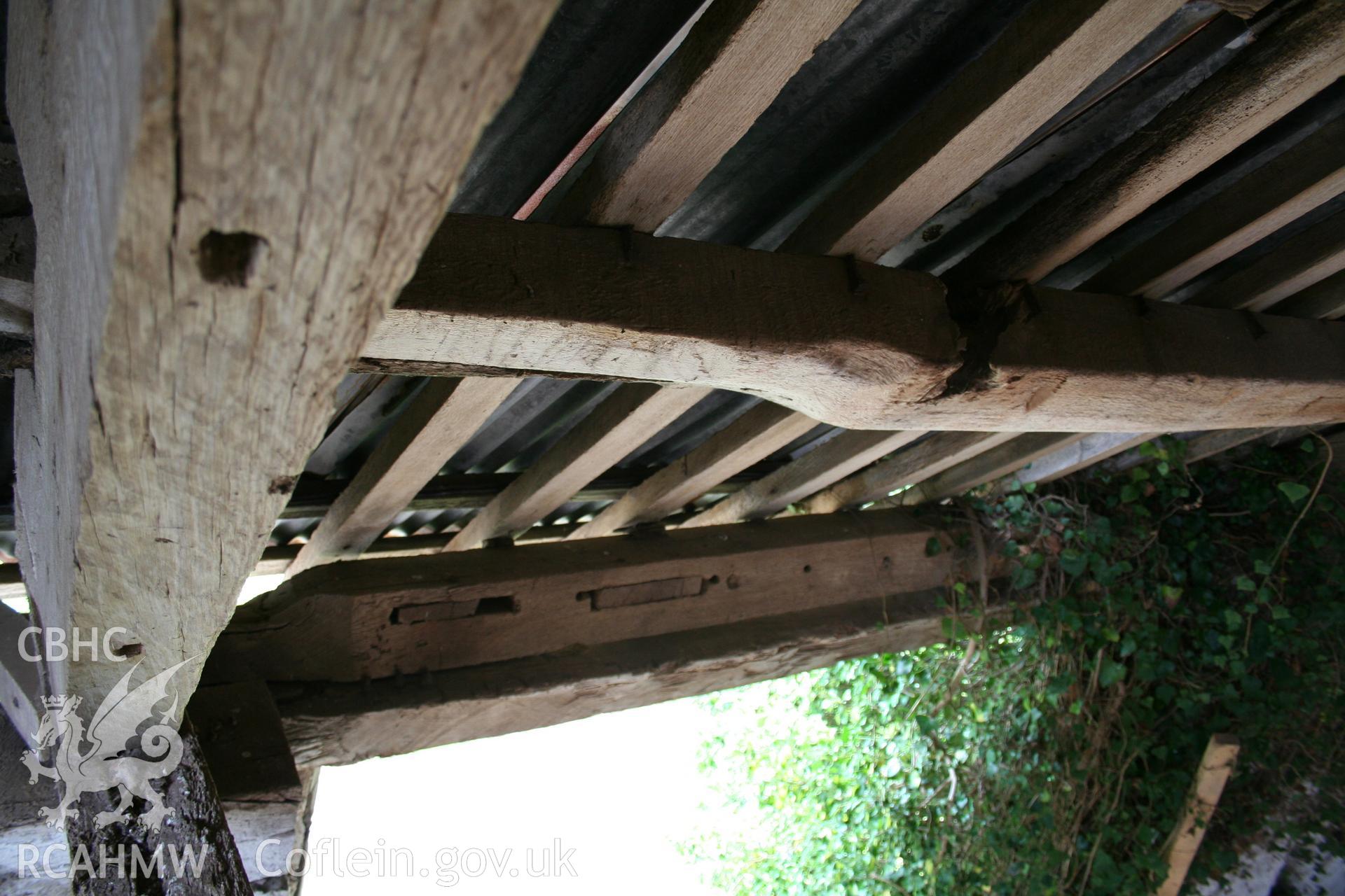 Interior of framed barn, wall plate (turned) at later threshing-bay doorway.