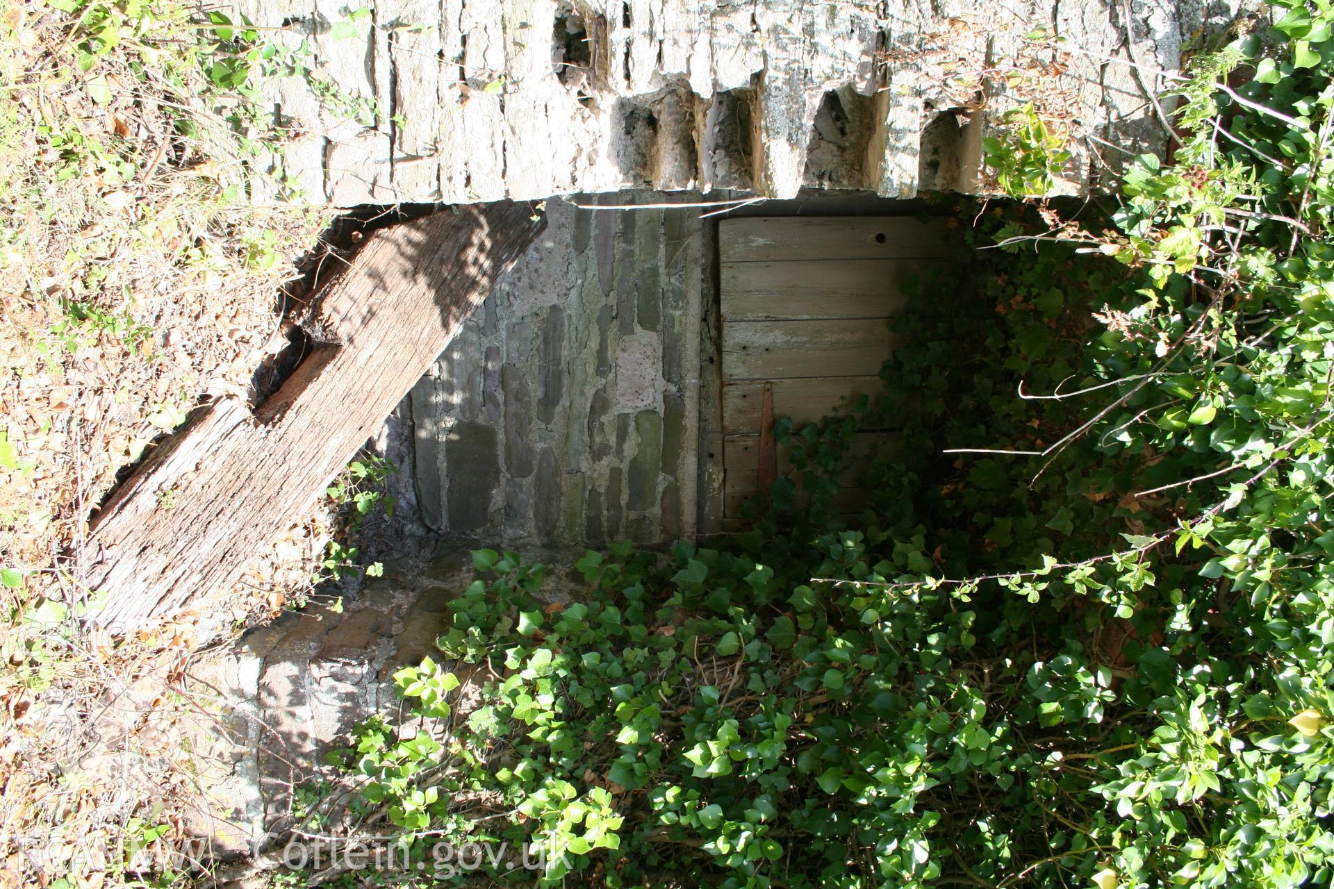 Exterior of south-west elevation of cowhouse/stable showing blocked doorway under stair to granary.