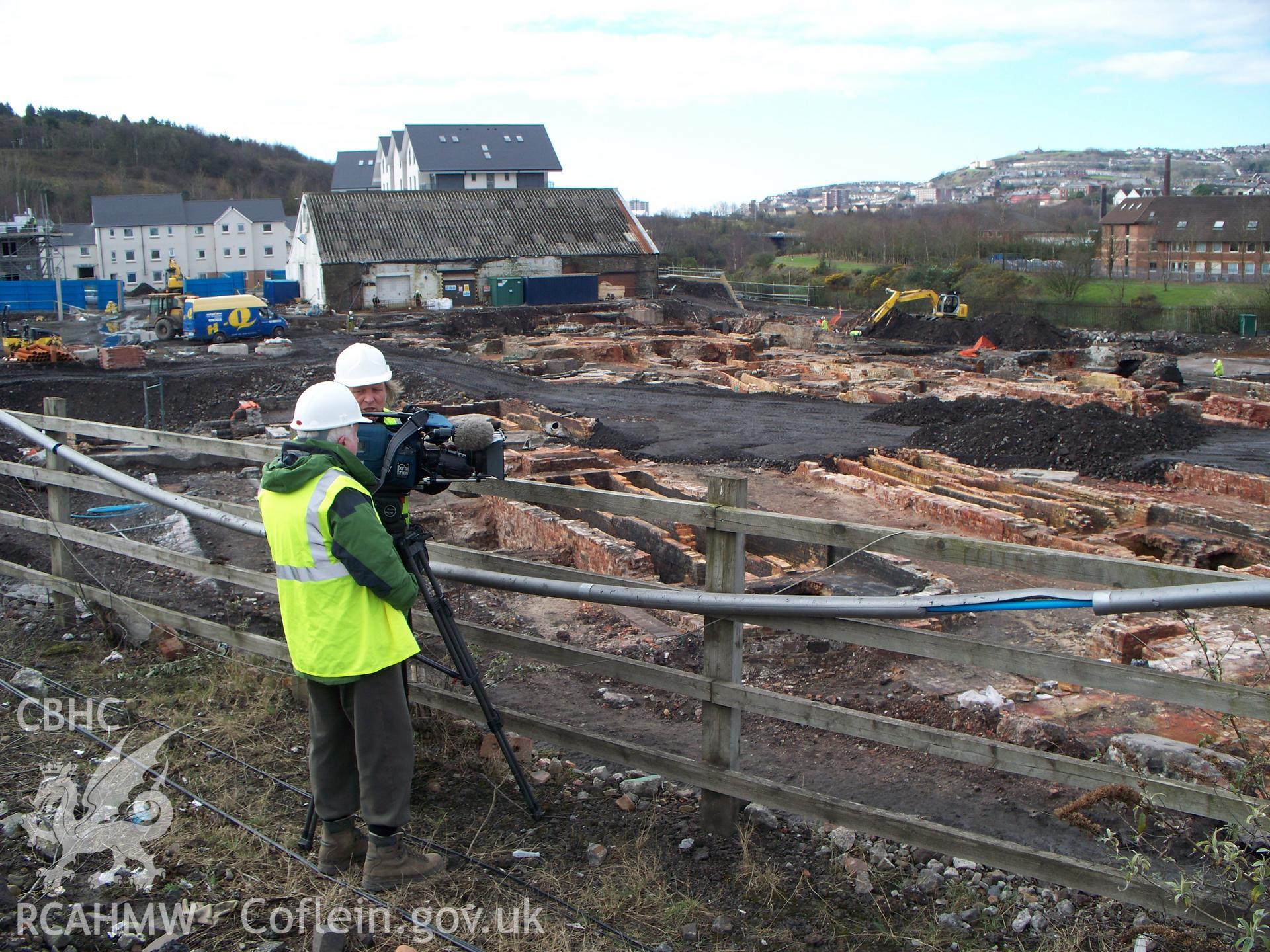 TV filming overlooking central site, Richard Edwards the producer to the left, access road covering centre of site, looking SW.