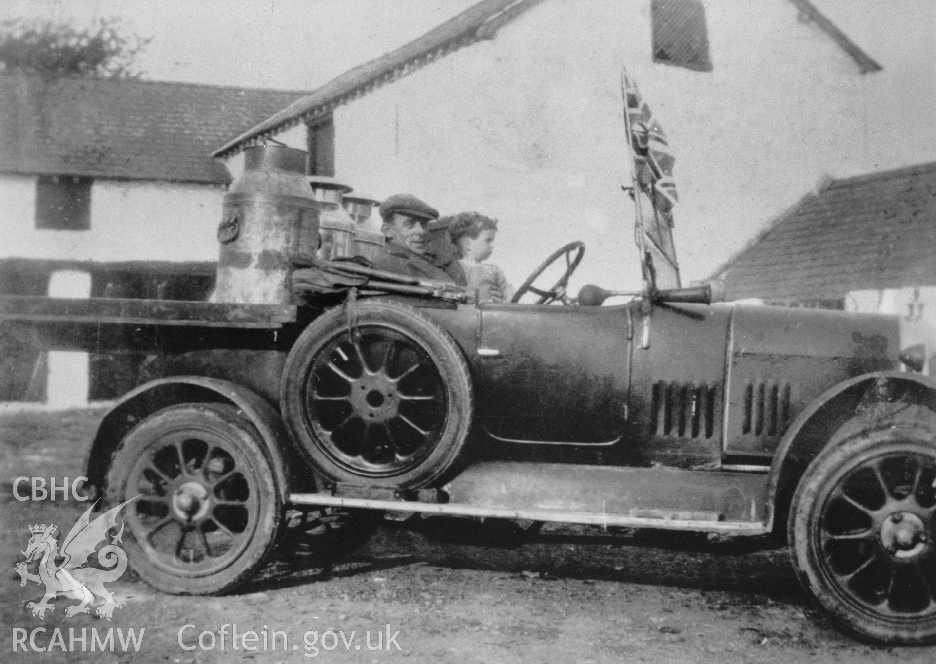 Copy of pre 1950 photo showing vintage car with milk churns on the back