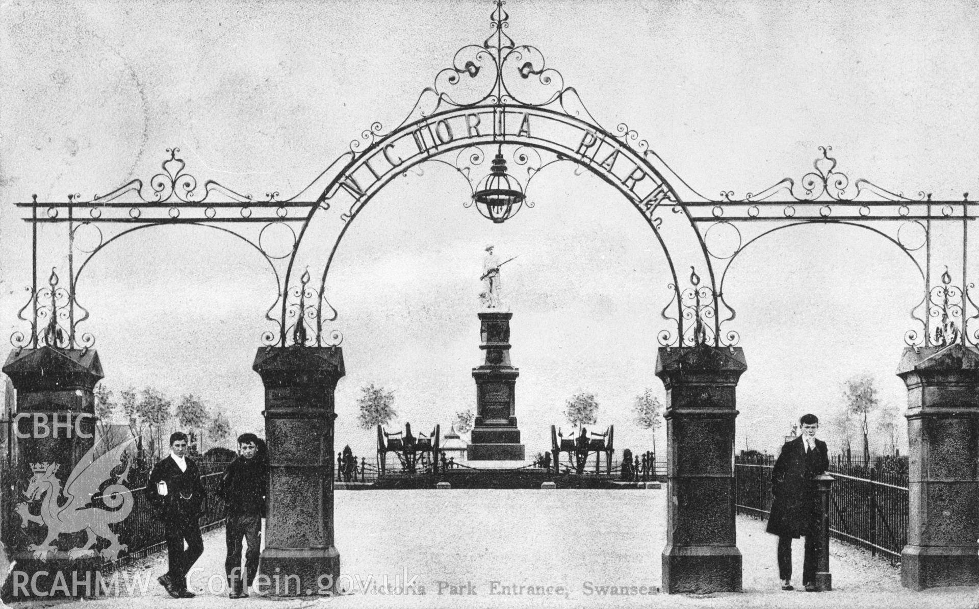 Copy of an early black and white photograph showing the entrance to Victoria Park, with the (now removed) war memorial in the background.