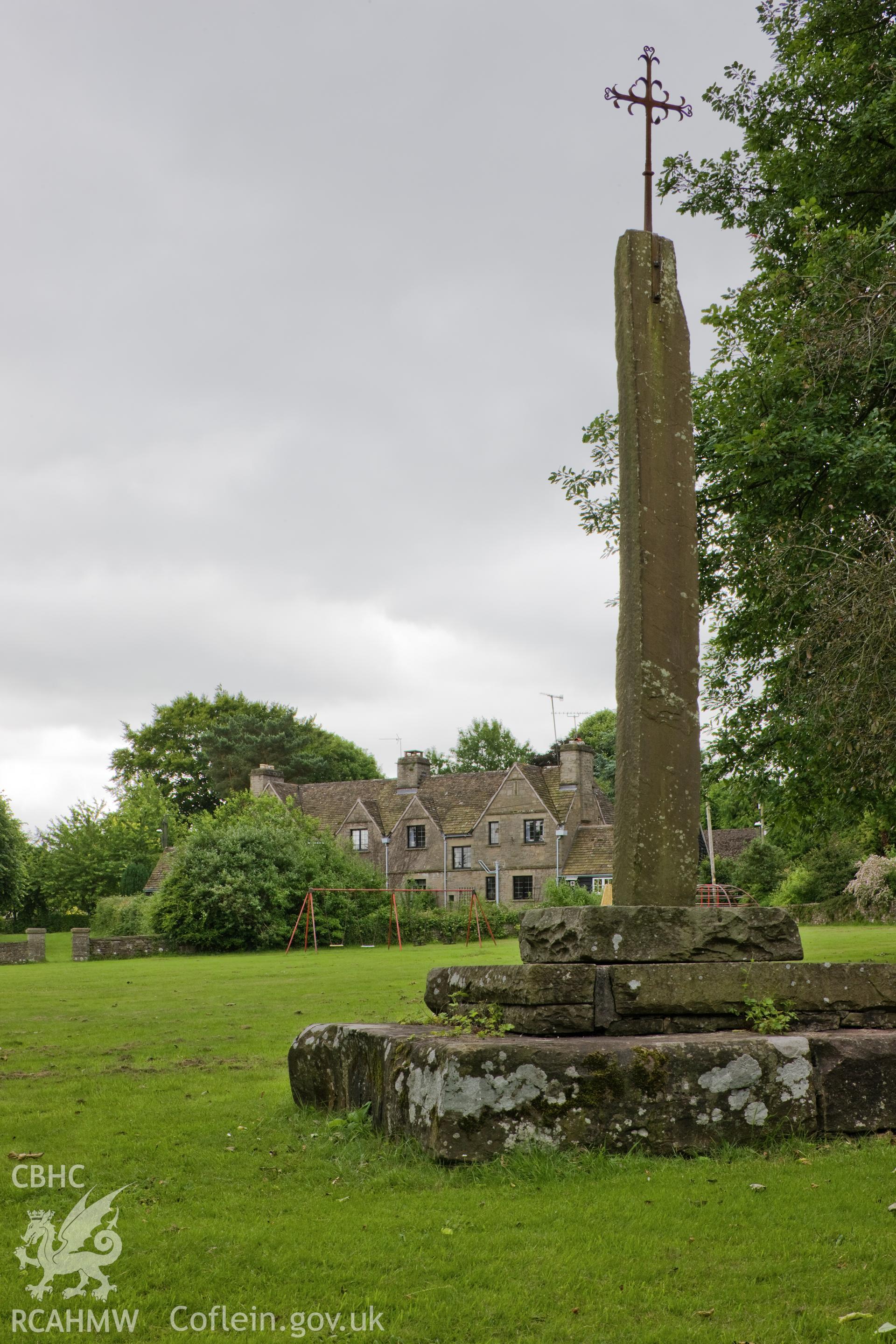 War memorial on green, with cottages in background.