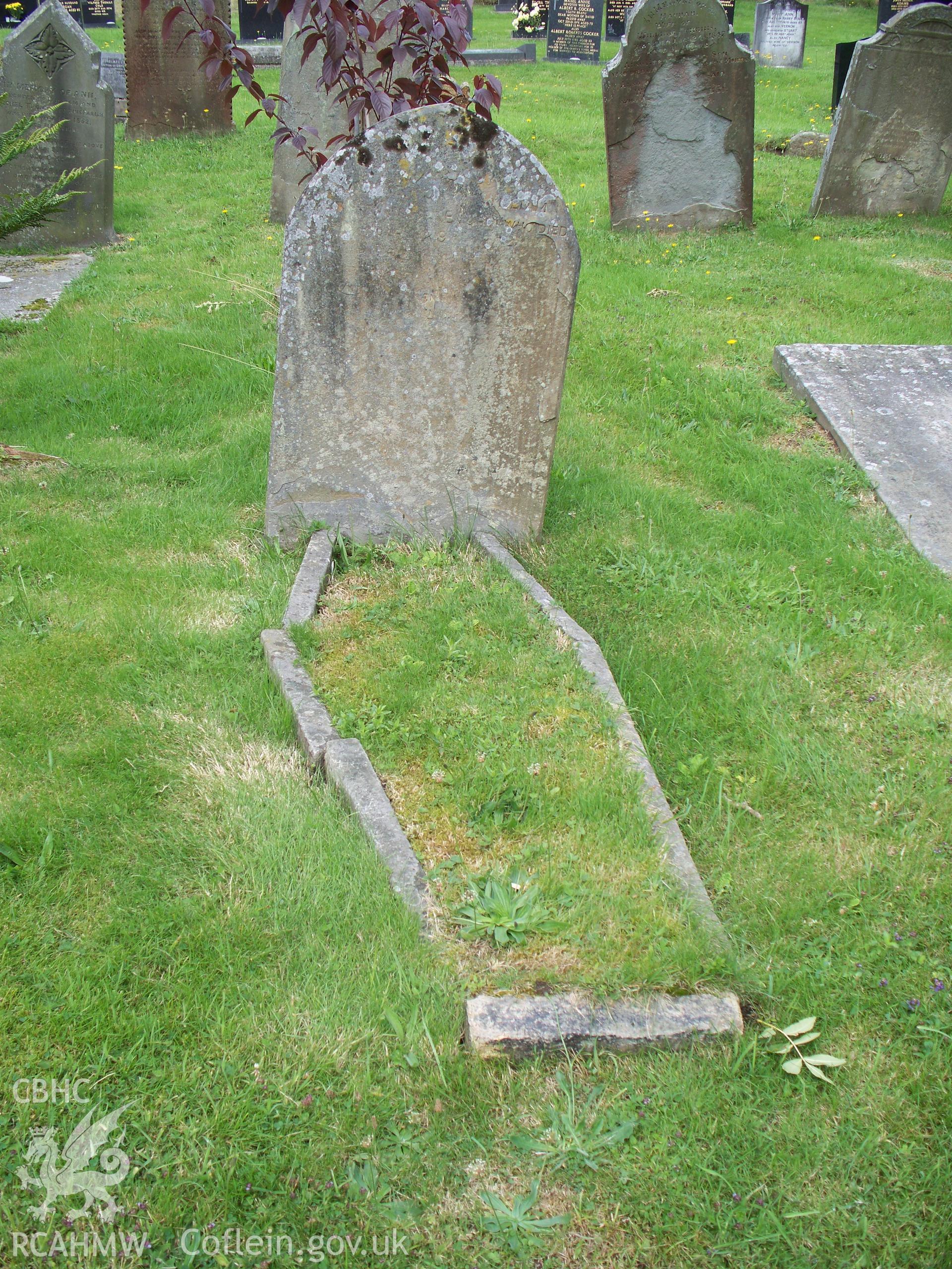 Flaking gravestone with coffin-shaped stone boundary.