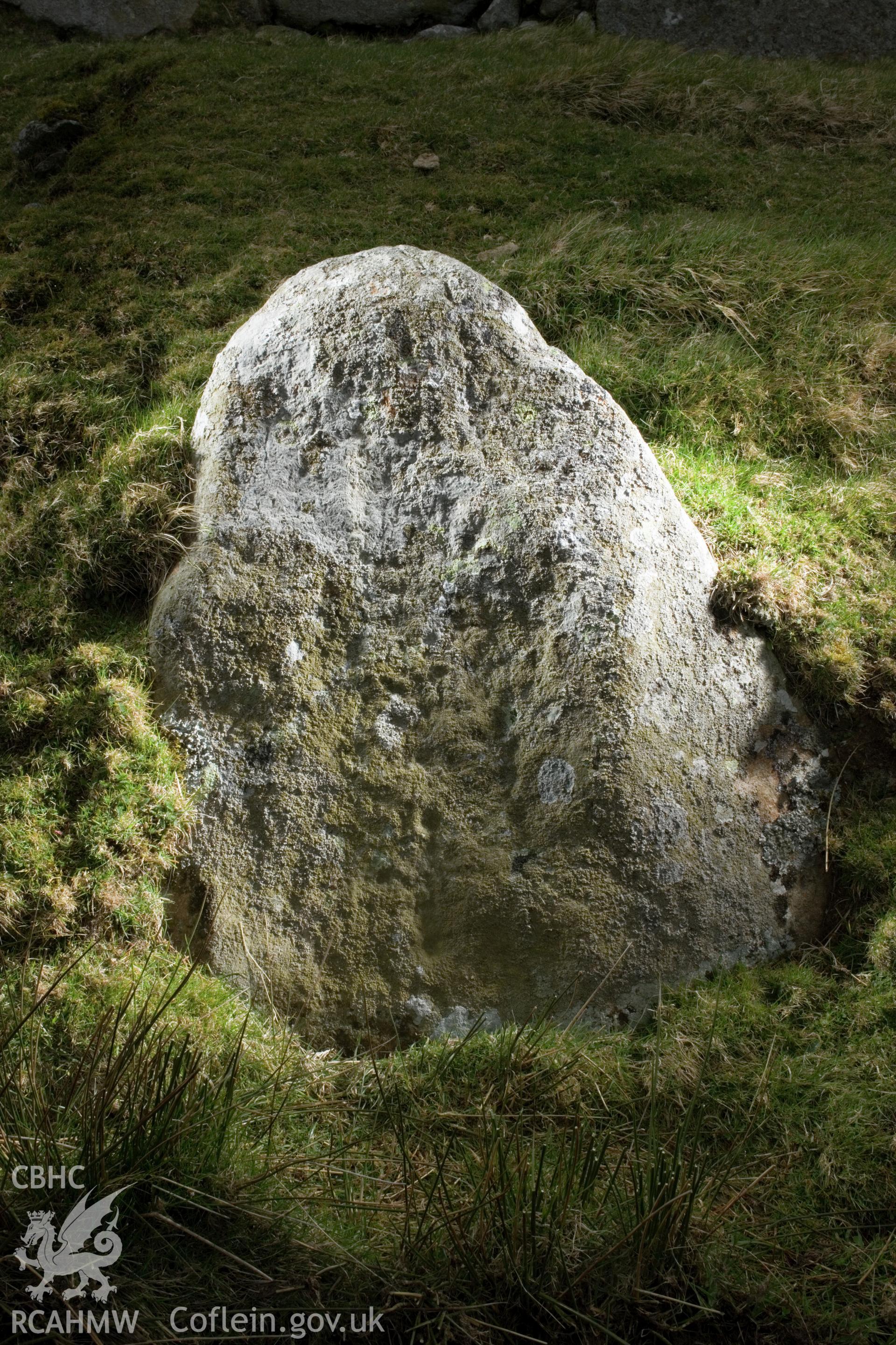 Cross carved stone (visible in middle of face, just below centre; taking up a third of the face).