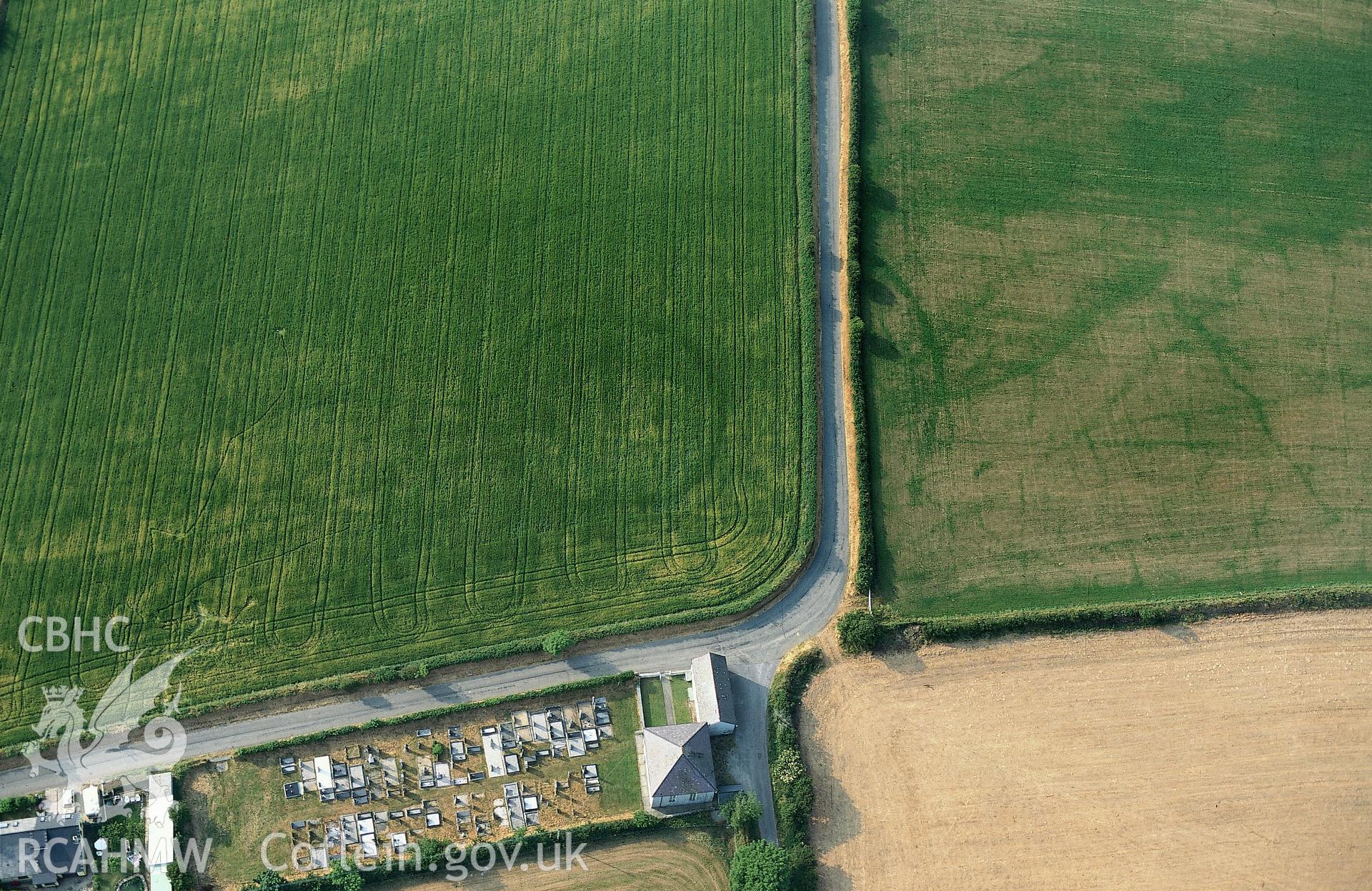 RCAHMW colour oblique aerial photograph of a cropmark enclosure east of Treferedd Uchaf taken on 08/07/1995 by C.R. Musson
