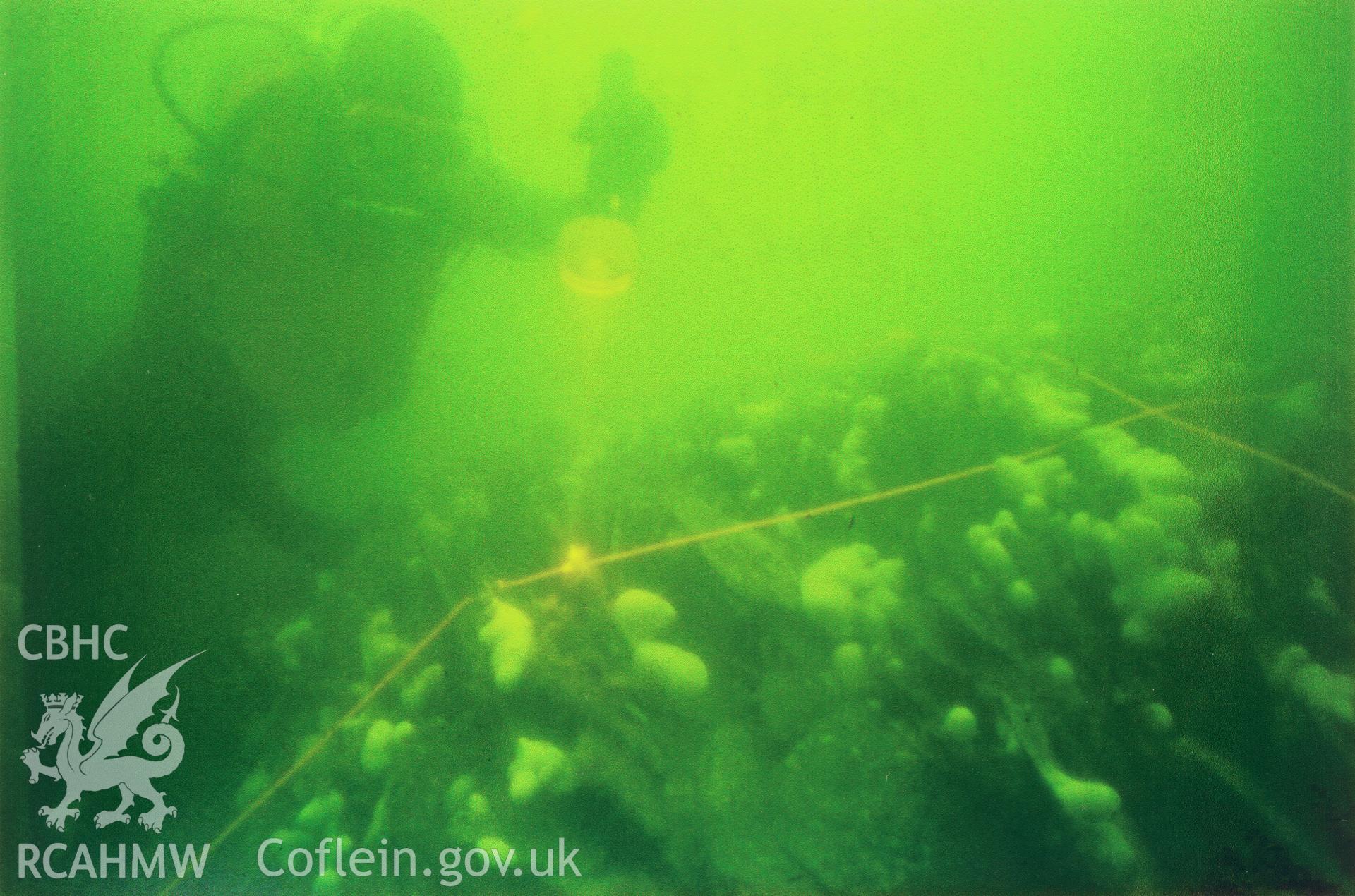 Digitized copy of a colour photograph showing diver on a slate mound during the 1978 survey of the Pwll Fanog Slate Wreck, copied from papers held in within the Protection of Wrecks Act 1973 Contractors archive (currently Wessex Archaeology).