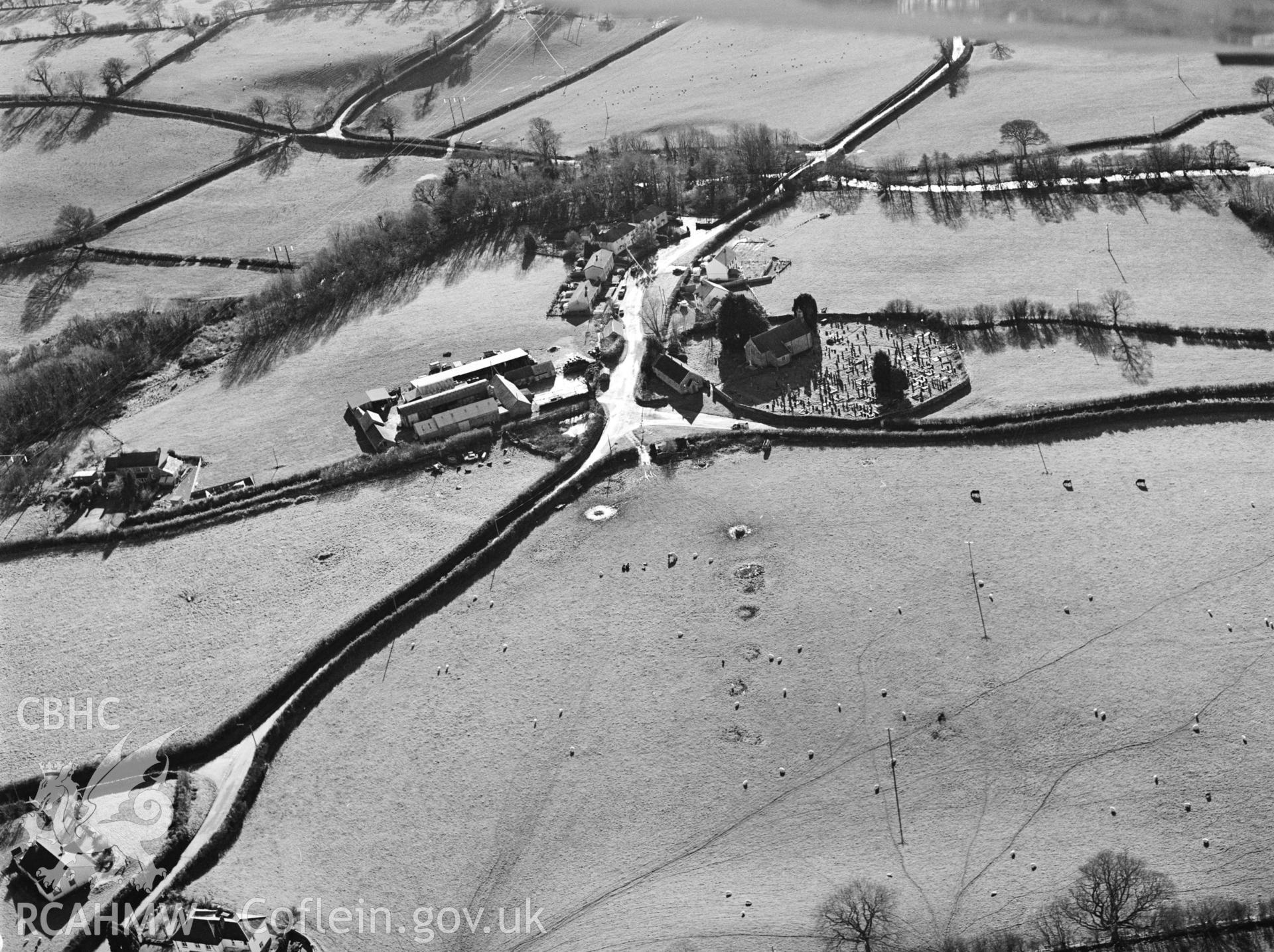 RCAHMW black and white oblique aerial photograph of St. Mary's Church, Llanfair Clydogau, with outer earthwork enclosure. Taken by Toby Driver on 15/11/2002