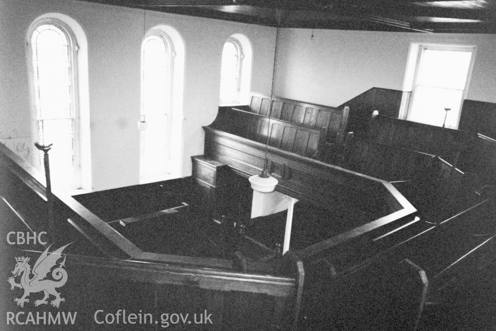 Digital copy of a black and white photograph showing an interior view of Seion Calvinistic Methodist Chapel, Llansadwrn, taken by Robert Scourfield, 1996.