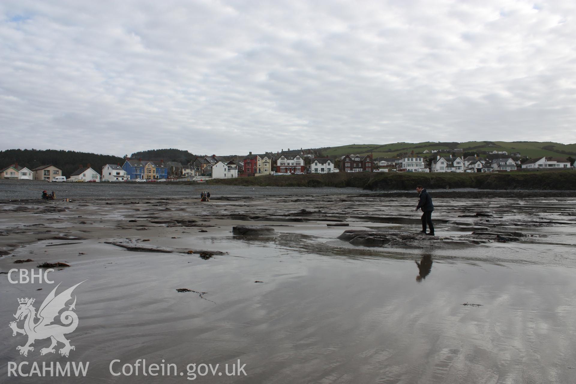 Borth submerged forest (between RNLI lifeboat station and upper Borth), looking southeast towards High street and Clarach road. Showing western extent of peat exposures at low tide(with Lampeter University staff memeber for scale)