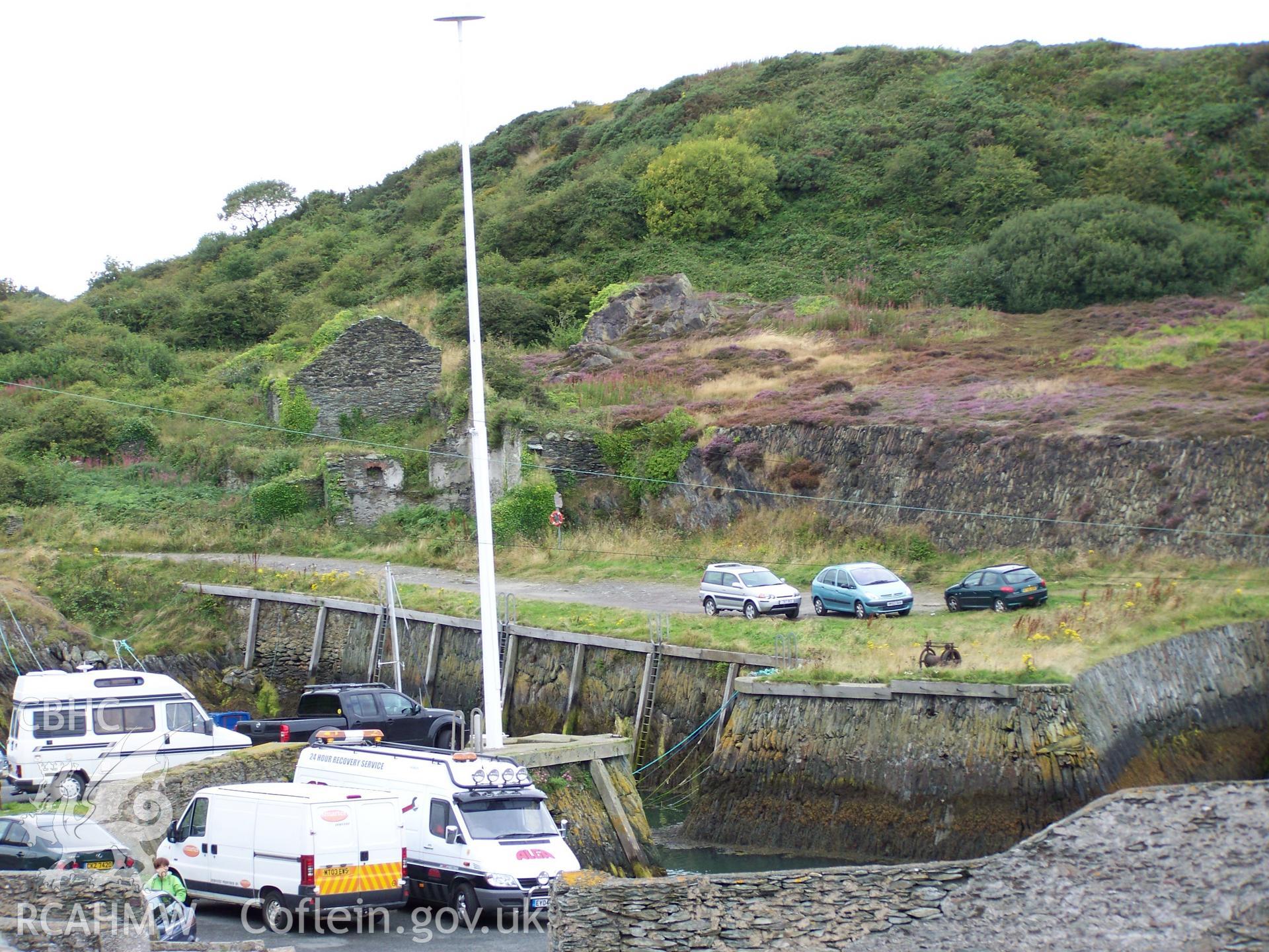 The roofless remains of some of the shipyard former workshops can be seen to the left of the picture with the back of the platform cut for the yard finished in drystone walling.