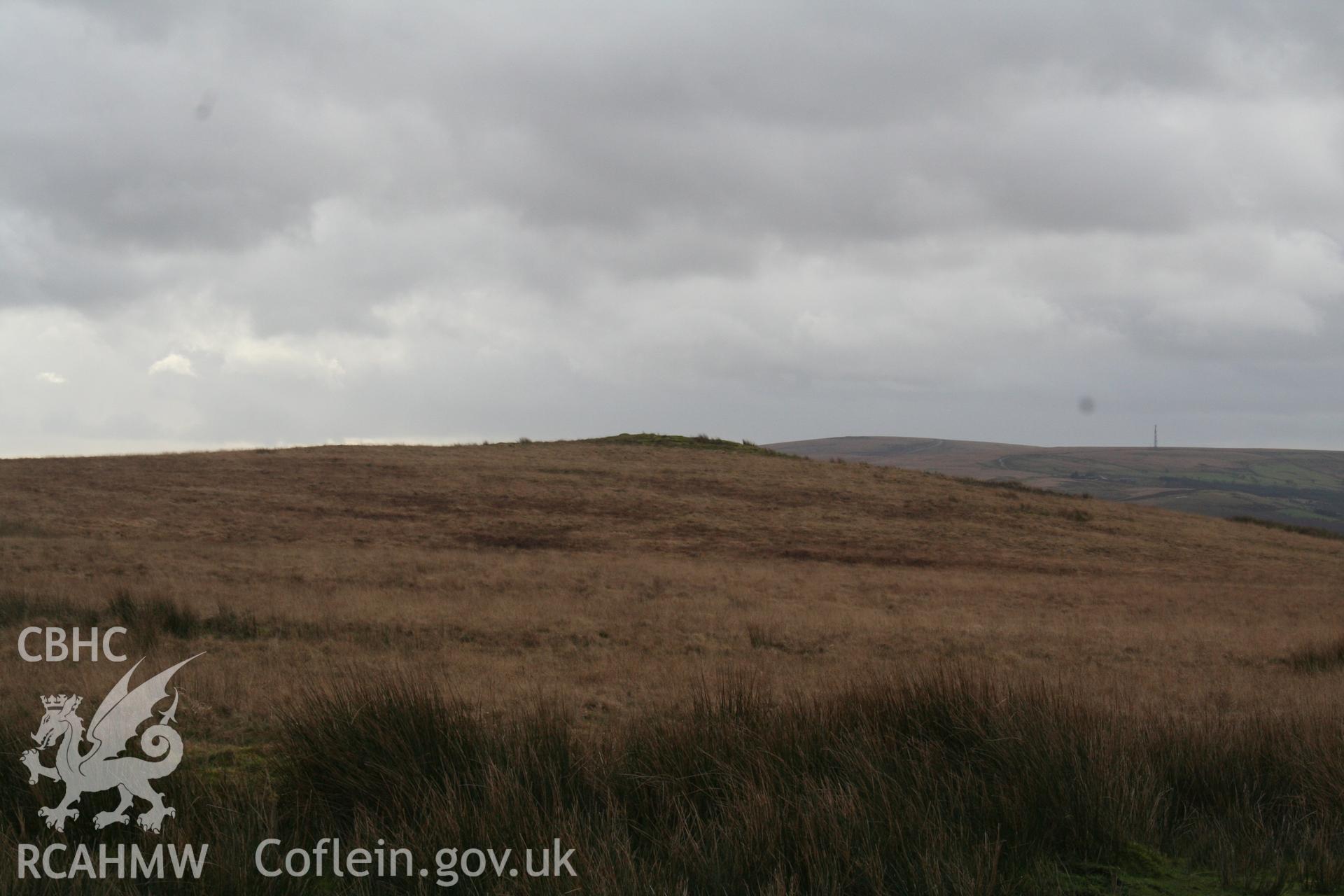 Distant view of cairn situated on local summit; from the north.
