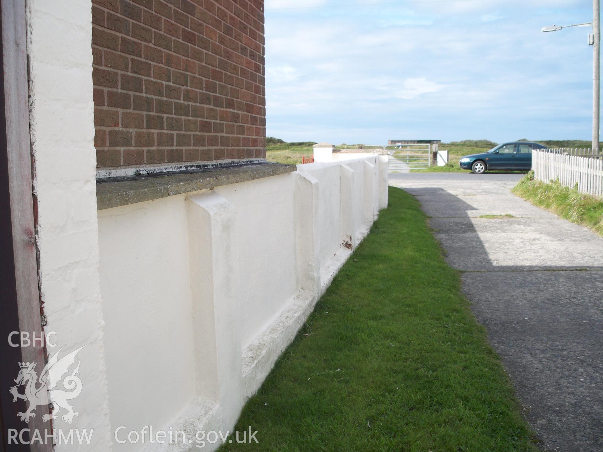 Rendered brick wall with buttresses to west of workshop along southern side of military access road