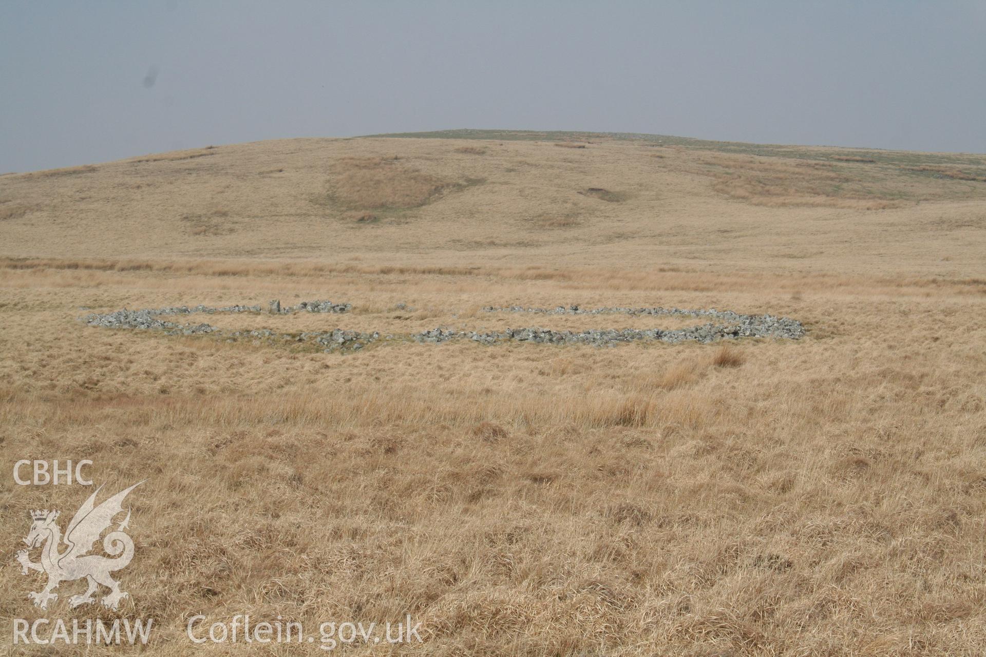Ring cairn in rolling moorland, seen from south; the ring is about 25m in overall diameter.