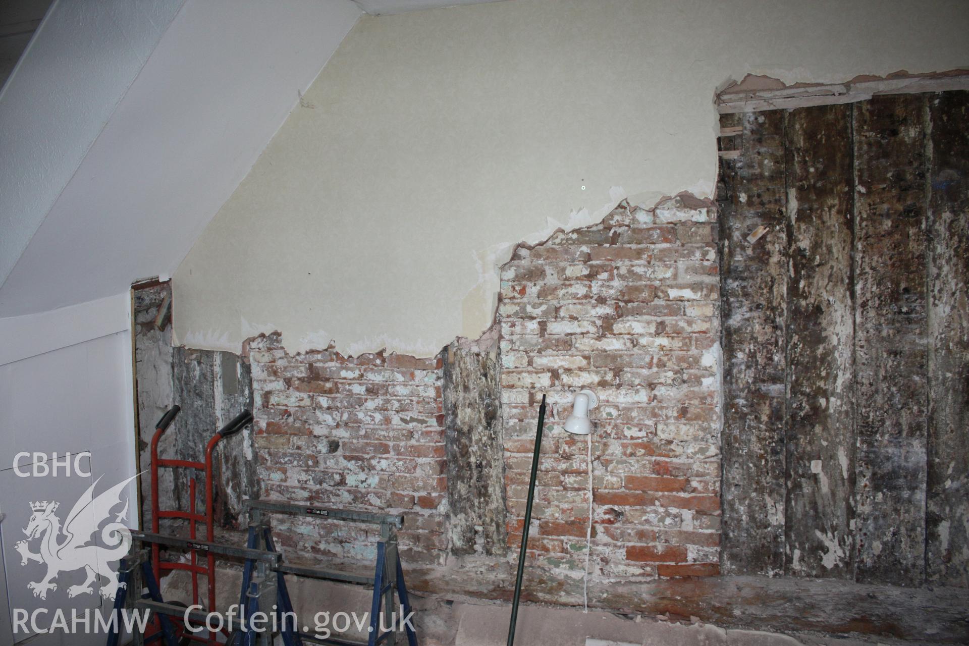 Internal; Living room, former service room, showing rear of post-and-panel partition and 17th centruy brick blocking.