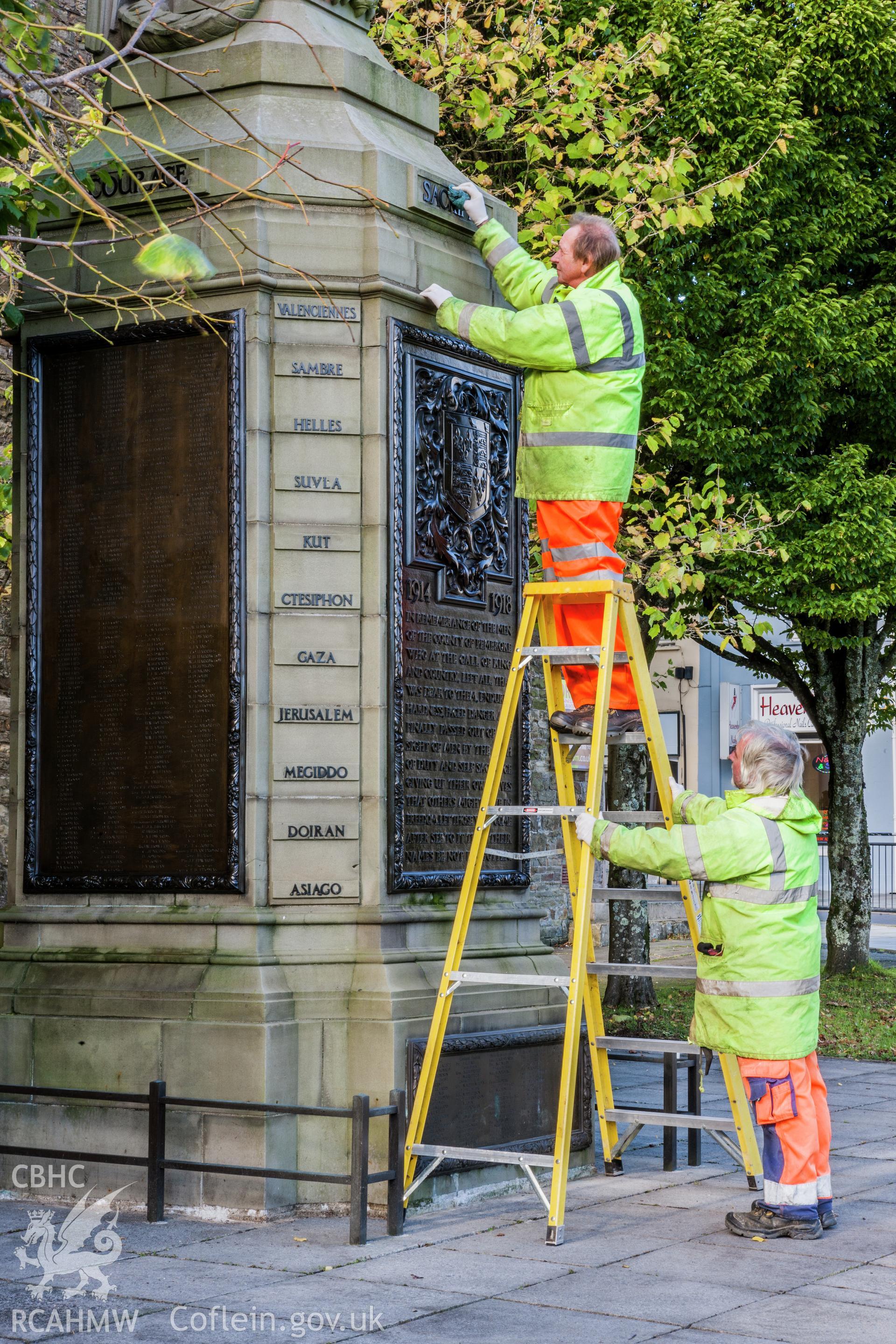 Council workers oiling metal work