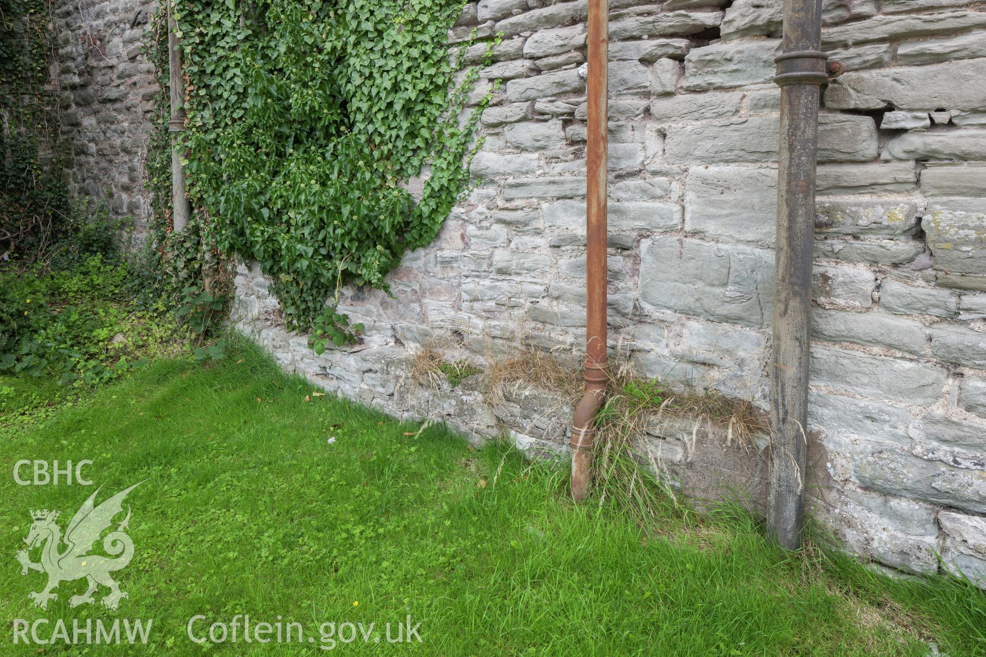 Stone plinth showing the rebuild line, straight joint between downpipes