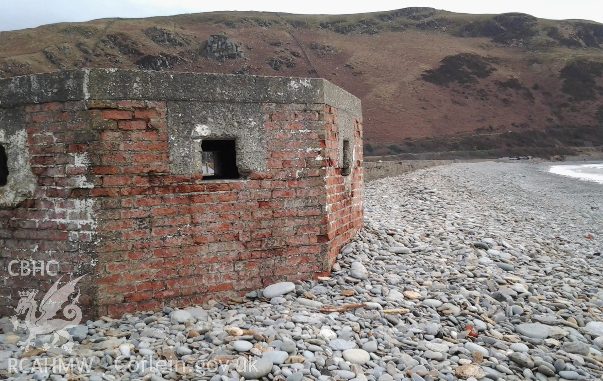 Northwest facing wall of pillbox showing firing loops remaining open and line of blocks extending southwards