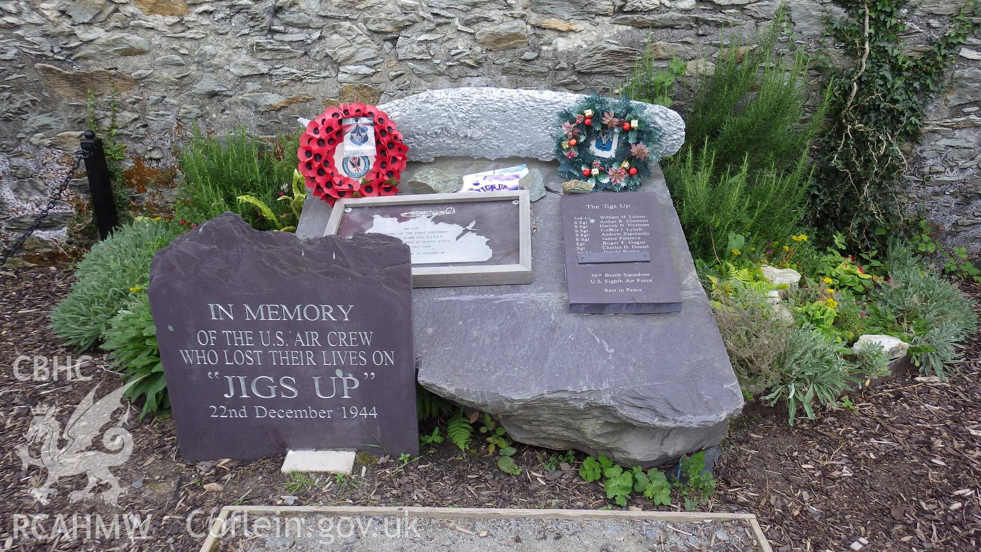 Memorial comprising upright inscribed stone, larger stone with name board and part of recovered propeller