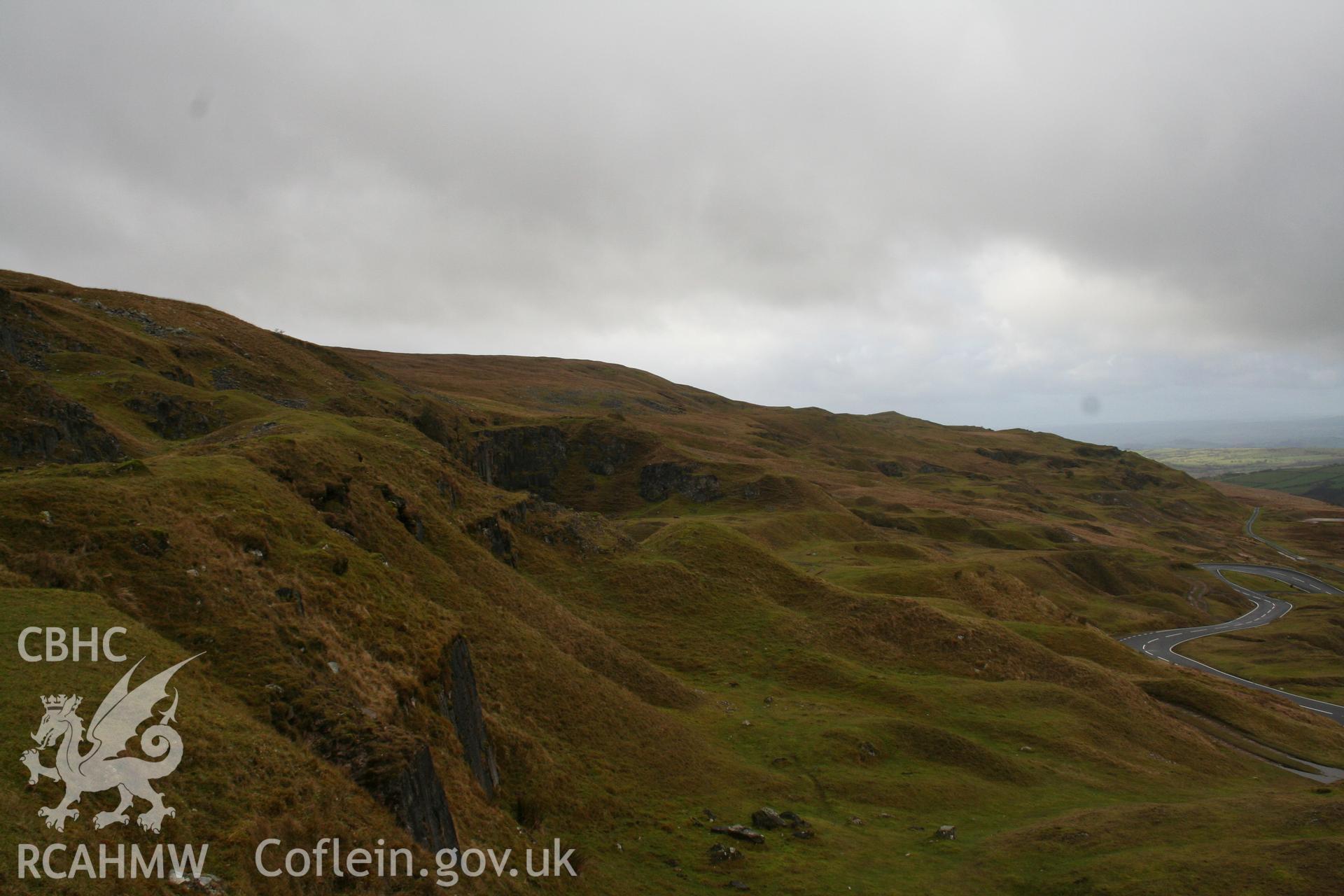 View of limestone quarries and old lime workings above the A4067, looking west towards area of NPRN 84105.