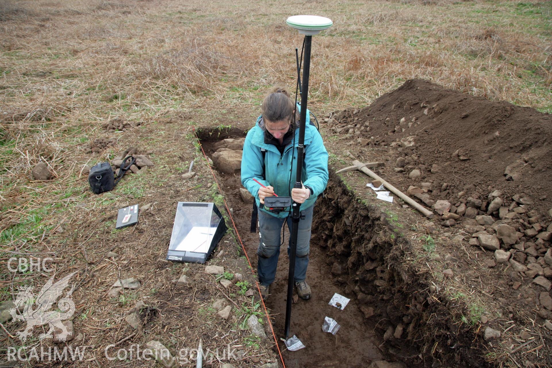 Skomer Island excavation of a burnt stone mound, Hut Group 8. Post excavation - L. Barker measuring in finds with a dGPS