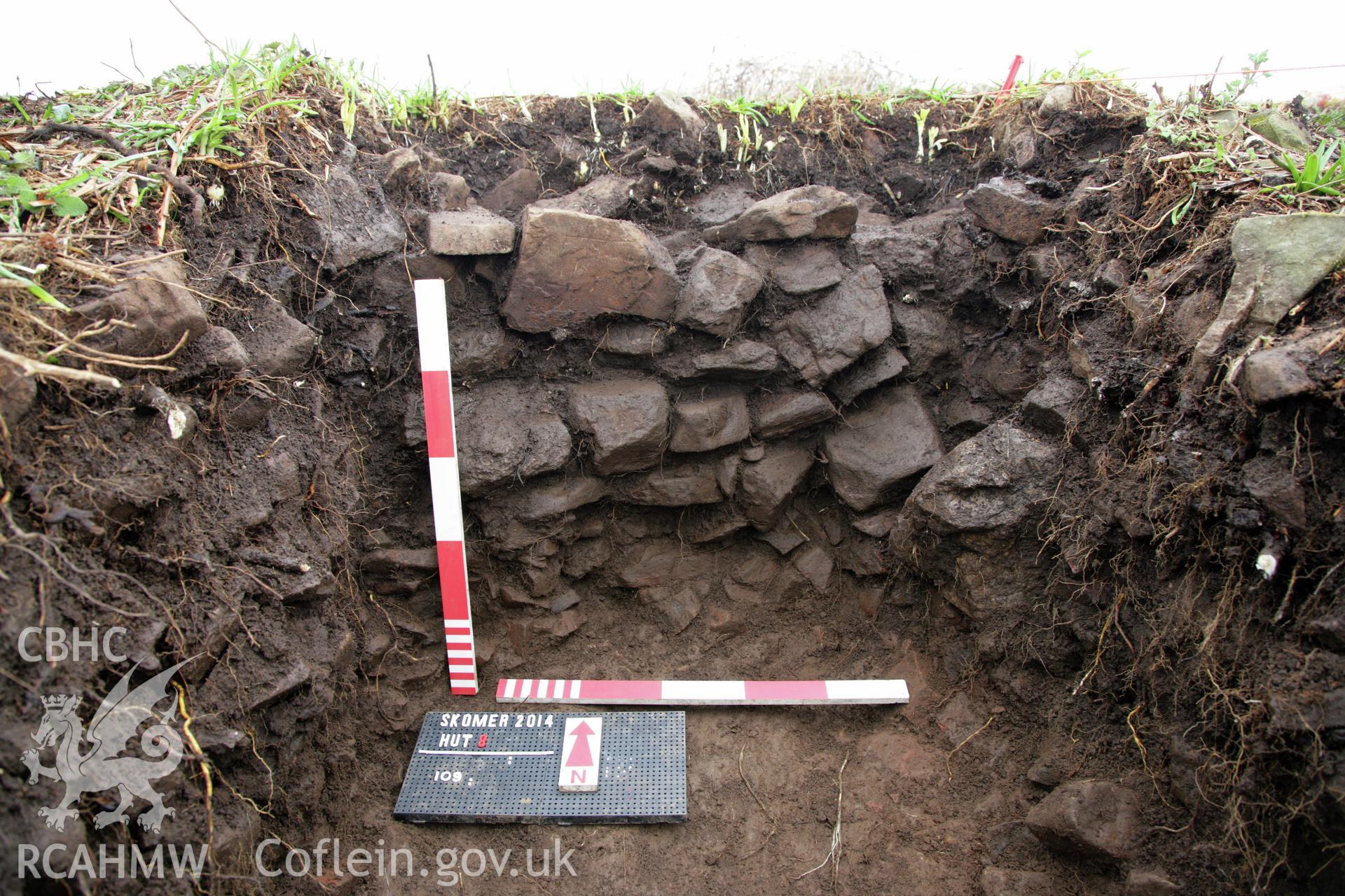 Skomer Island excavation of a burnt mound, Hut Group 8.  Excavation in progress view of the external face of the west roundhouse, context 109, overlying an earlier field lynchet, context 111