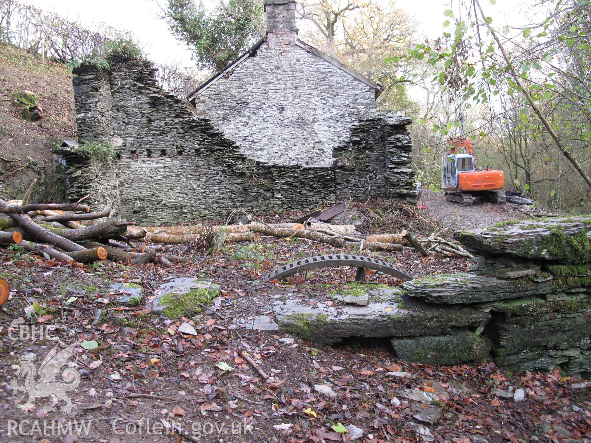 View from the northwest of Fron Factory, Rhayader, showing part-buried gear wheel.