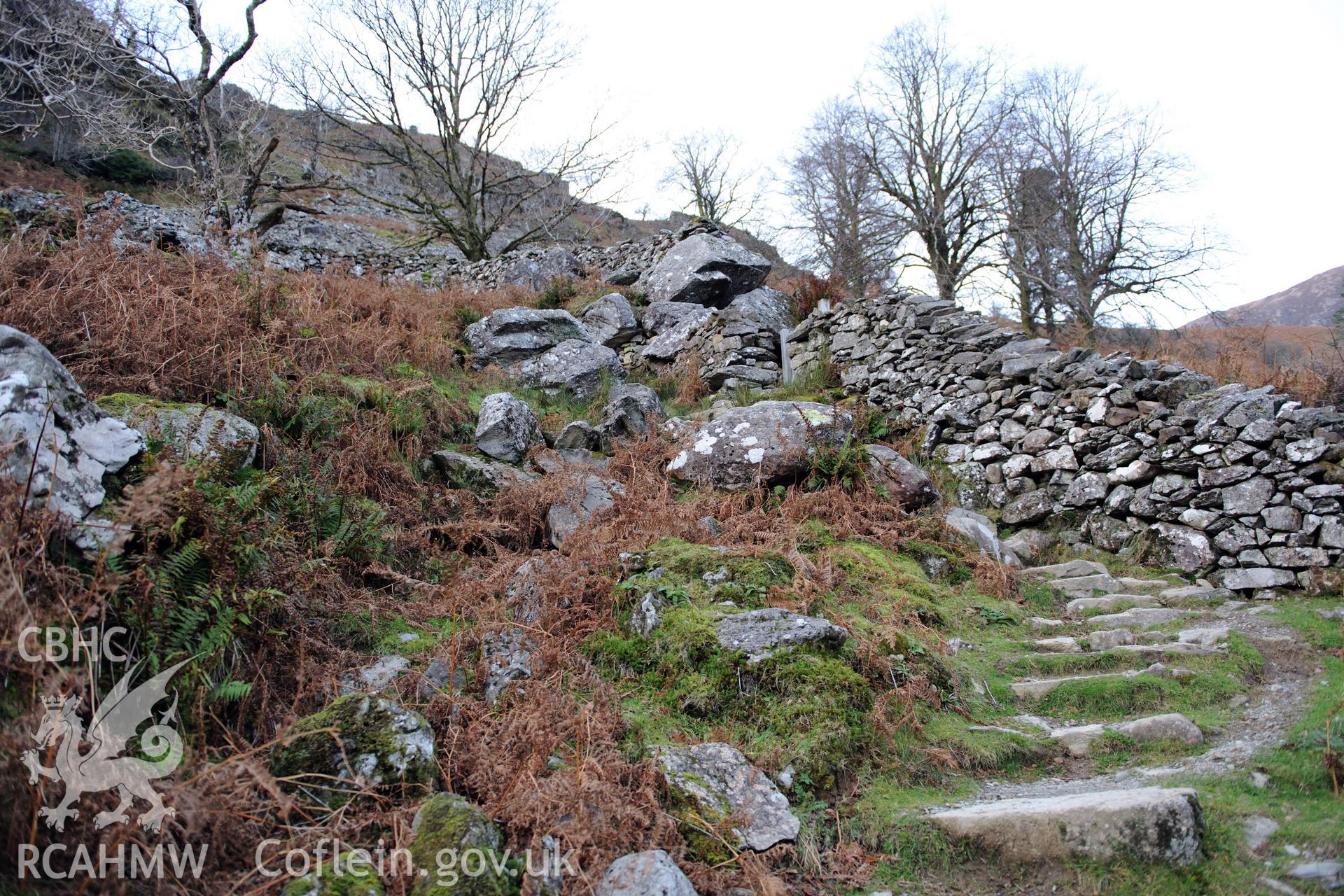 Photo survey of find spot of Tal-y-llyn hoard, beneath naturally-propped boulder alongside path. View approaching boulder