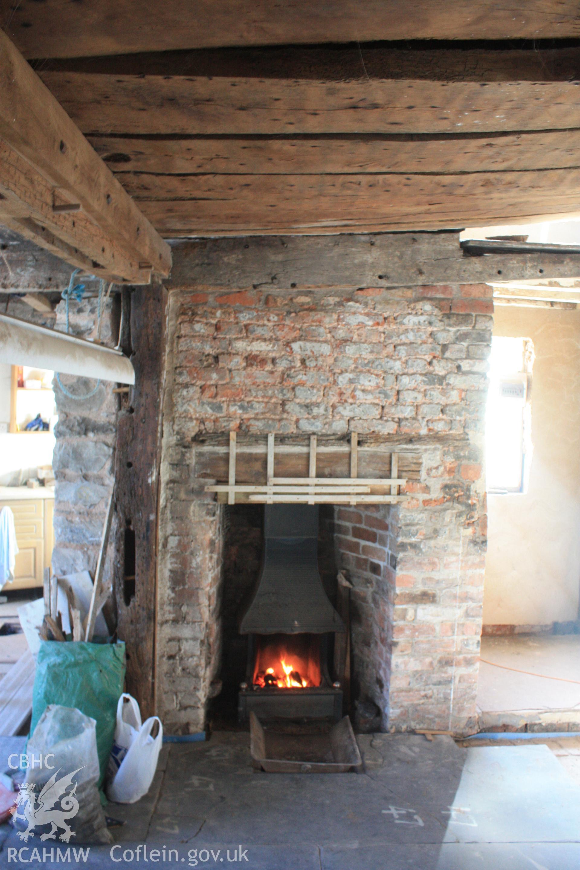 Interior: red brick fireplace, with reused timber for bressummer. Also showing girt beam with peg holes indicating stud locations.