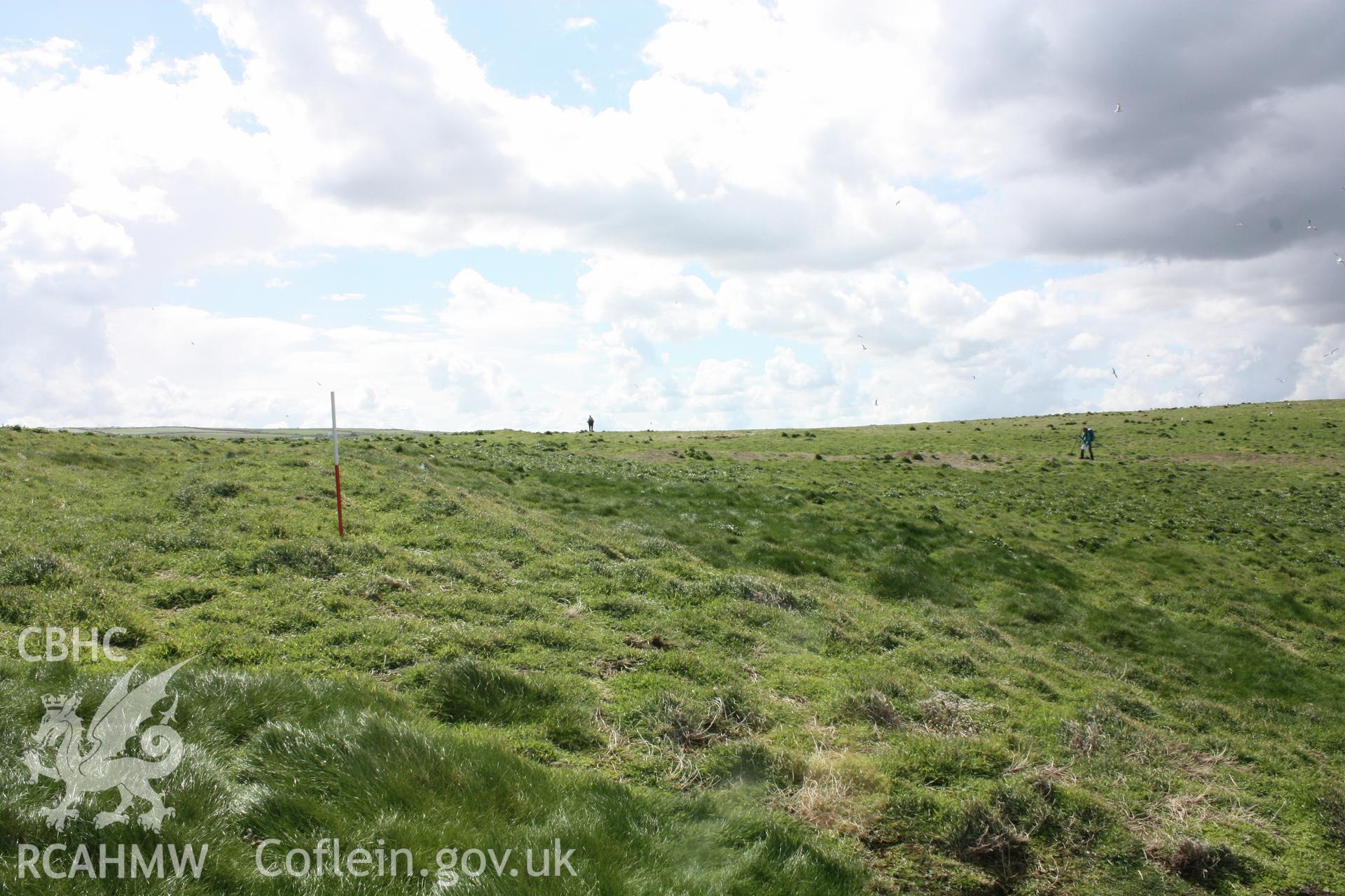 Looking south-east along the bank  defining the eastern edge of the promontory enclosure .  The central figure stands on linear bank (NPRN 309339) traces of which survive corssing the interior of the enclosure.