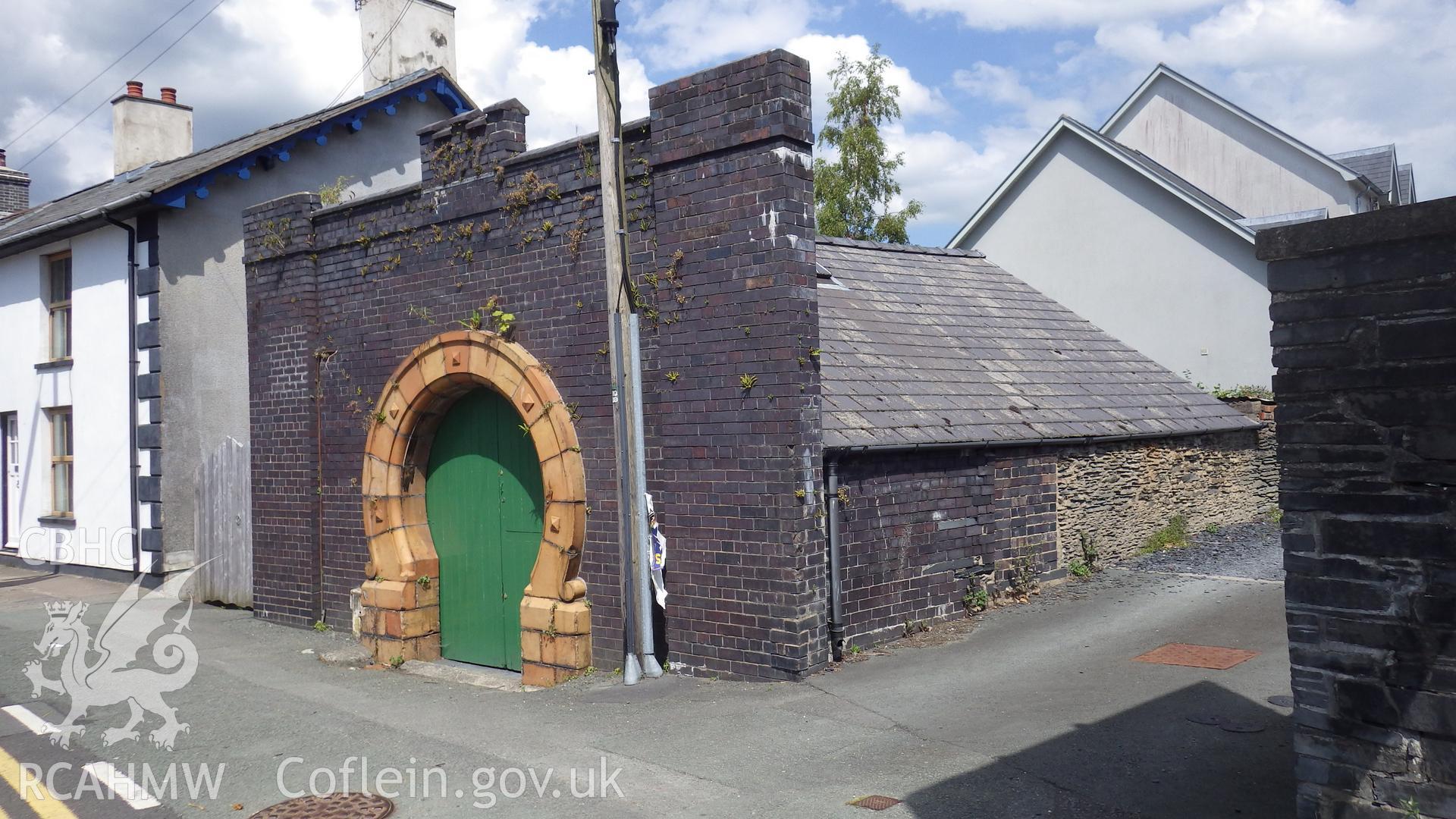 Smithy viewed from southwest, showing rough stone building behind decorative frontage