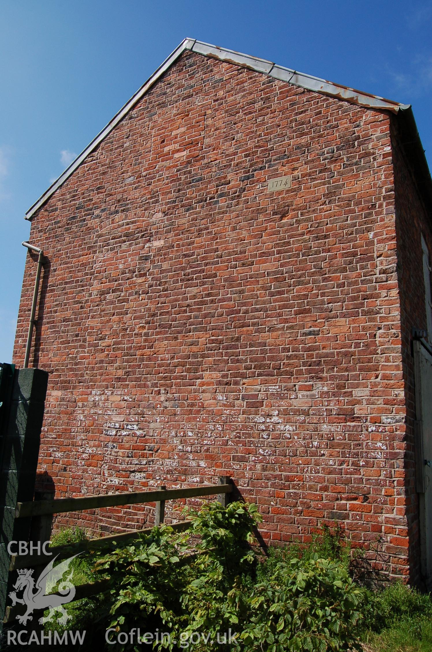 Digital photograph showing view of exterior of barn with date stone, at Marchwiel Old Hall
