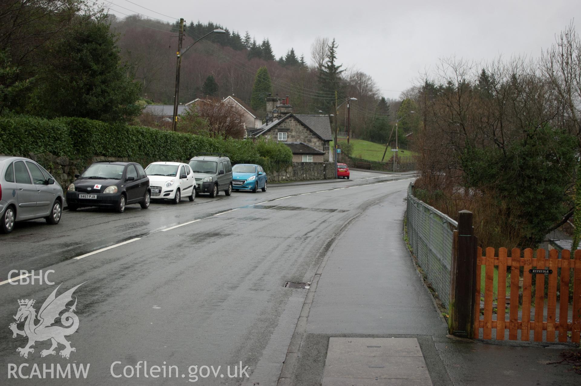 Marian Mawr archaeological assessment; section C-D, view from E showing view along street showing pipe route in pavement, showing former entrance to Bryngwyn, taken by Robert Evans of Gwynedd Archaeological Trust, 5th February 2016.