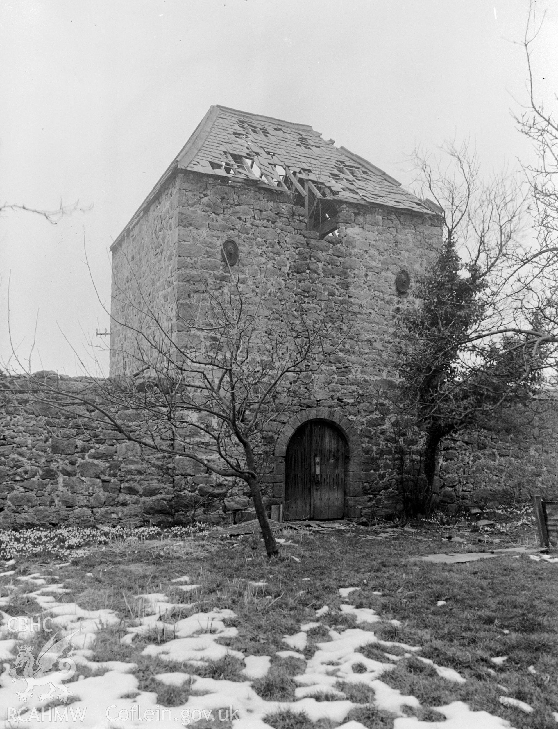 A dovecote made of stone with a dilapidated slate hipped roof.