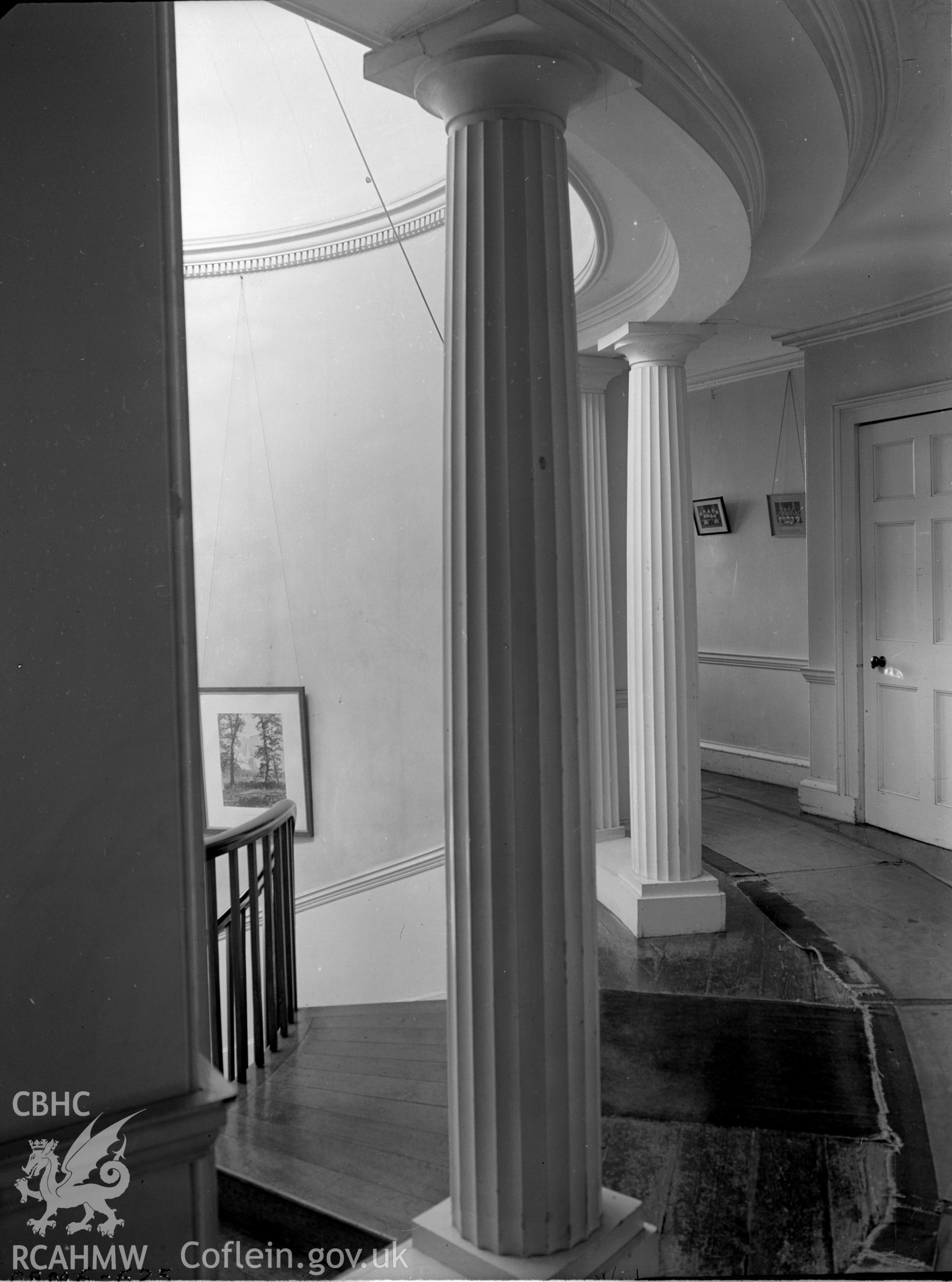 A curved landing, staircase opening, supported by two Greek Doric columns.