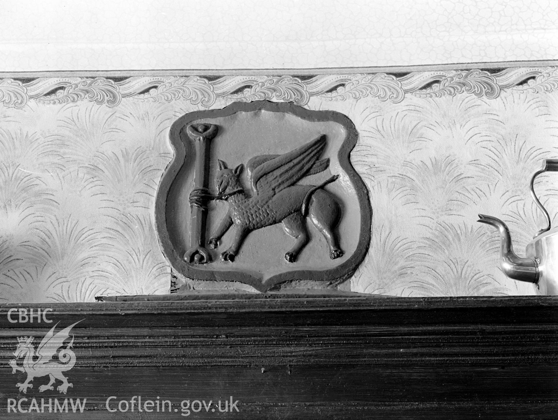 A mould above the fireplace in the kitchen depicting a Griffin.