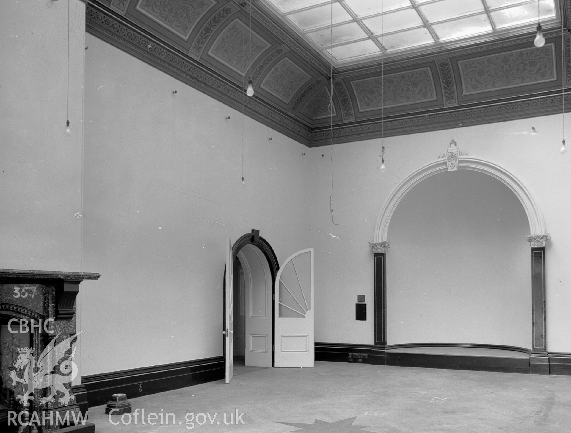 A view of a ballroom, with an arched double doorway, glass ceiling and a large arched alcove.