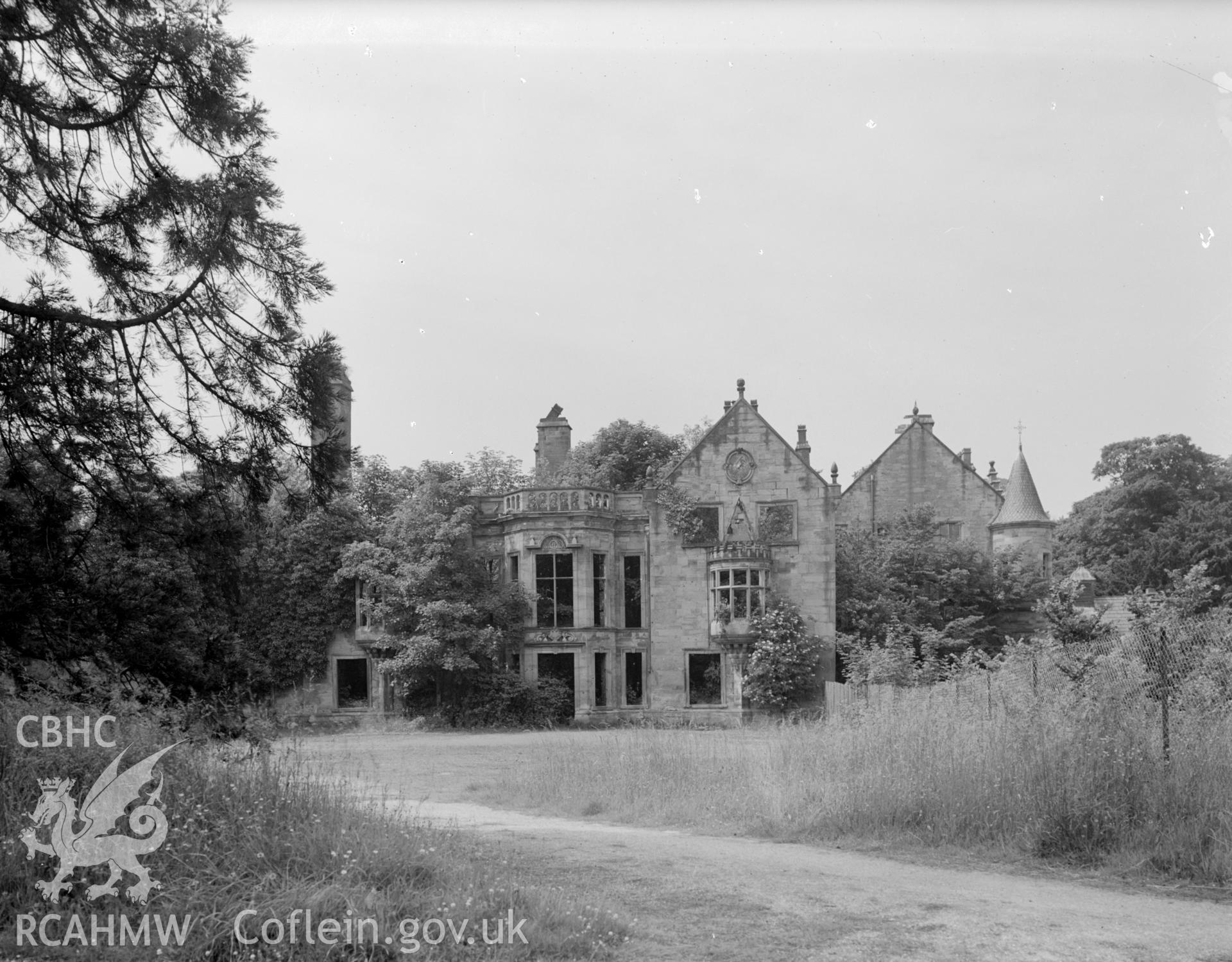 A view of a dilapidated country house. Trees growing through the structure.