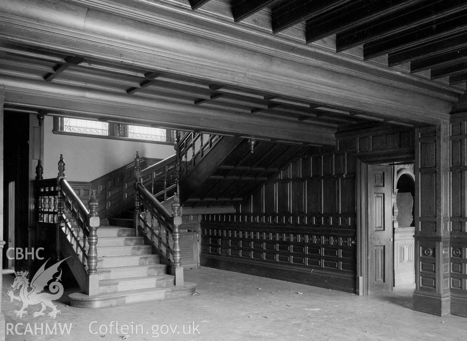 A wooden staircase and banister. Wood panelling on the hall walls.