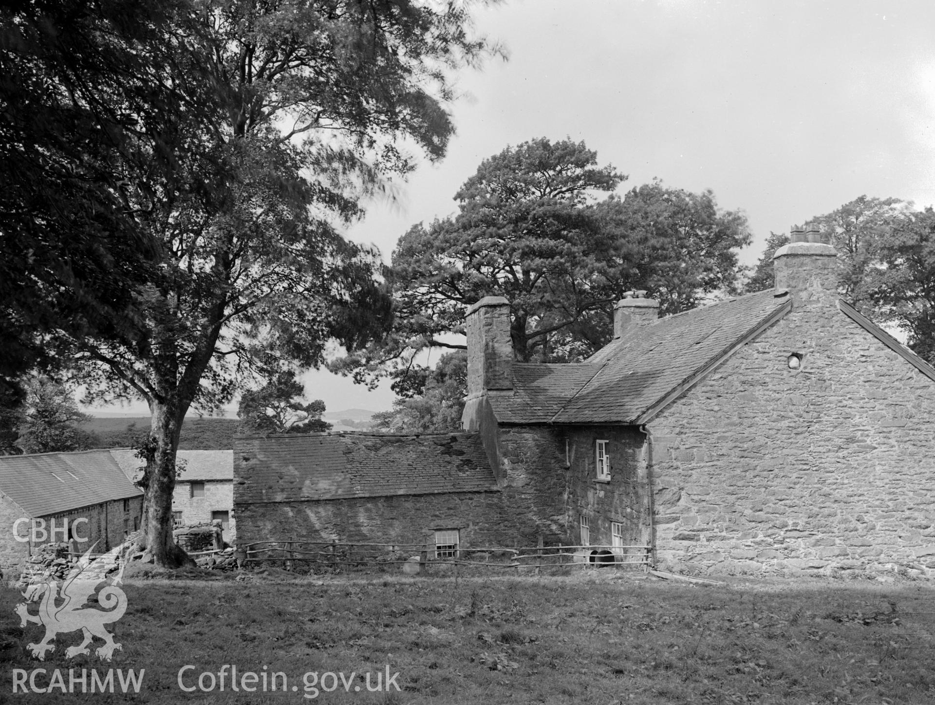 A view of the back of the building showing a one storey extension, as well as stone out buildings.