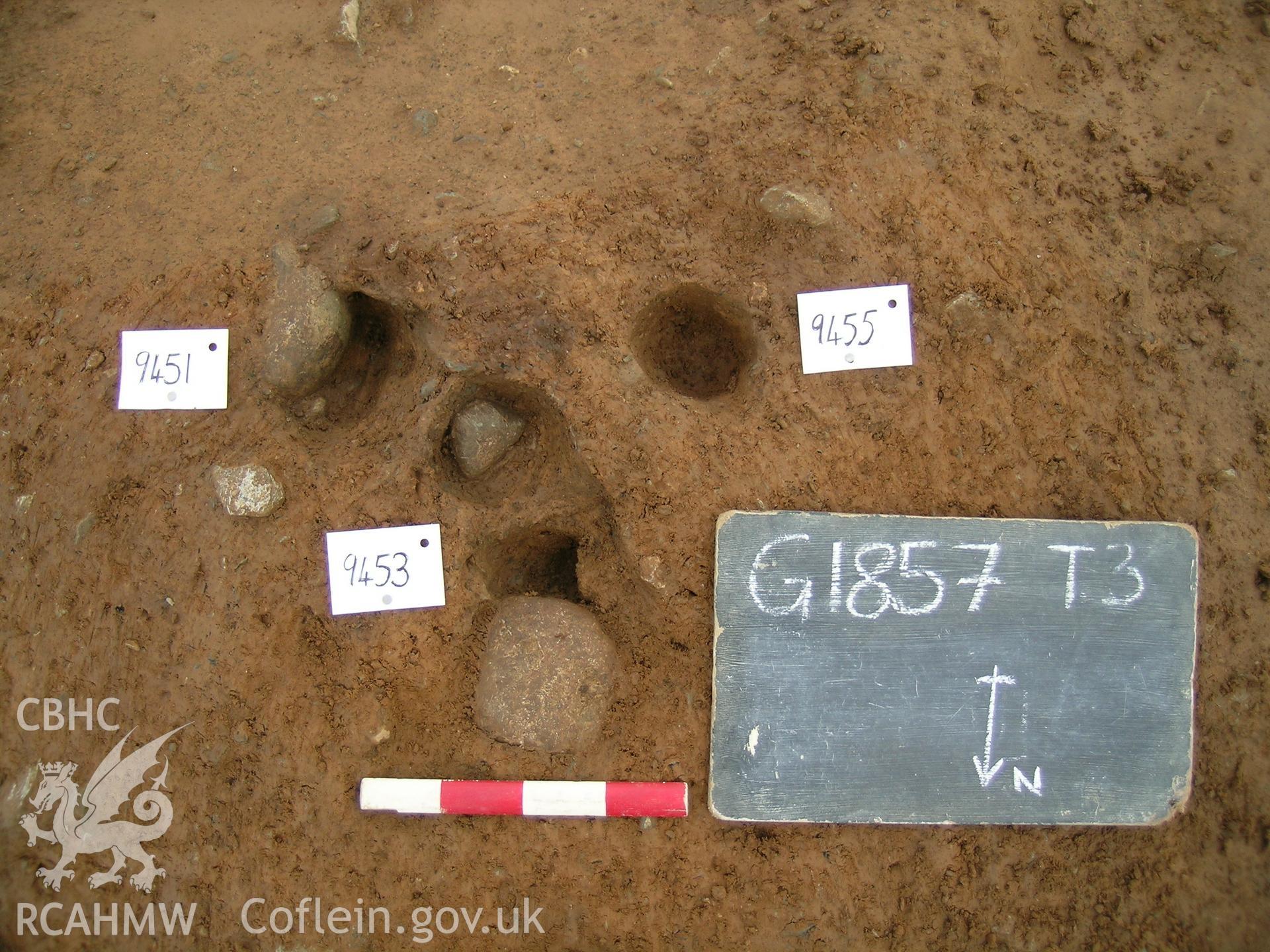 Digital photograph from excavation of Parc Bryn Cegin, Llandygai, by Gwynedd Archaeological Trust. stakeholes 9451, 9453, + 9455, from N (numbers refer to context records). Scale 0.2m.