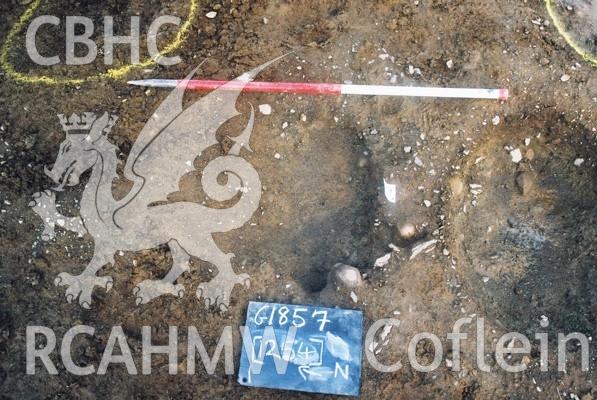 Photograph from excavation of Parc Bryn Cegin, Llandygai, by Gwynedd Archaeological Trust. Sub rectangular pit (1265) [1264] (misnumbered in shots), from E (numbers refer to context records). Scale 1x1m.