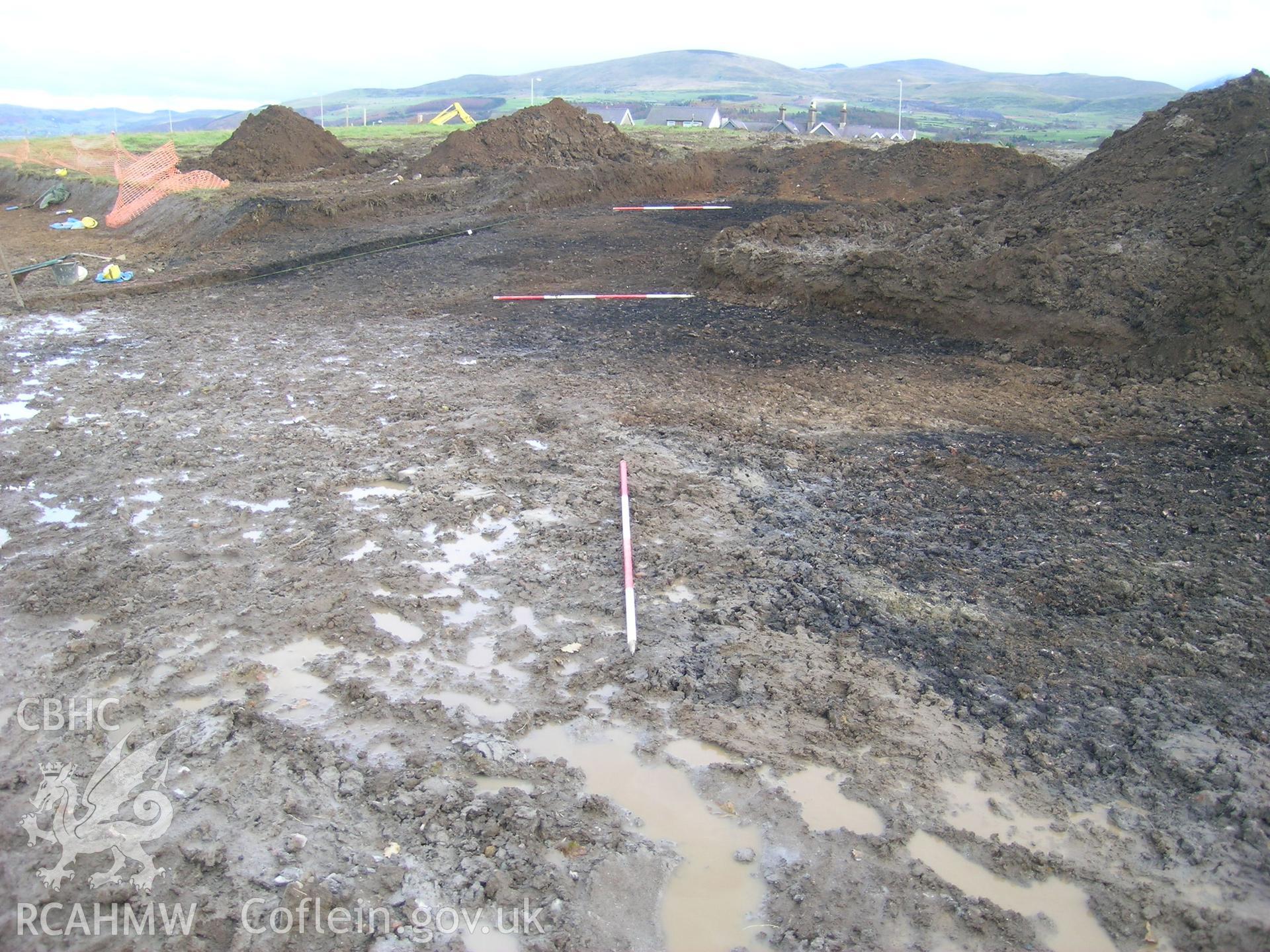 Digital photograph from excavation of Parc Bryn Cegin, Llandygai, by Gwynedd Archaeological Trust. Burnt mounds by the top of T2 by haul road (2176) and (2287), from W (numbers refer to context records). Scale 3x2m.
