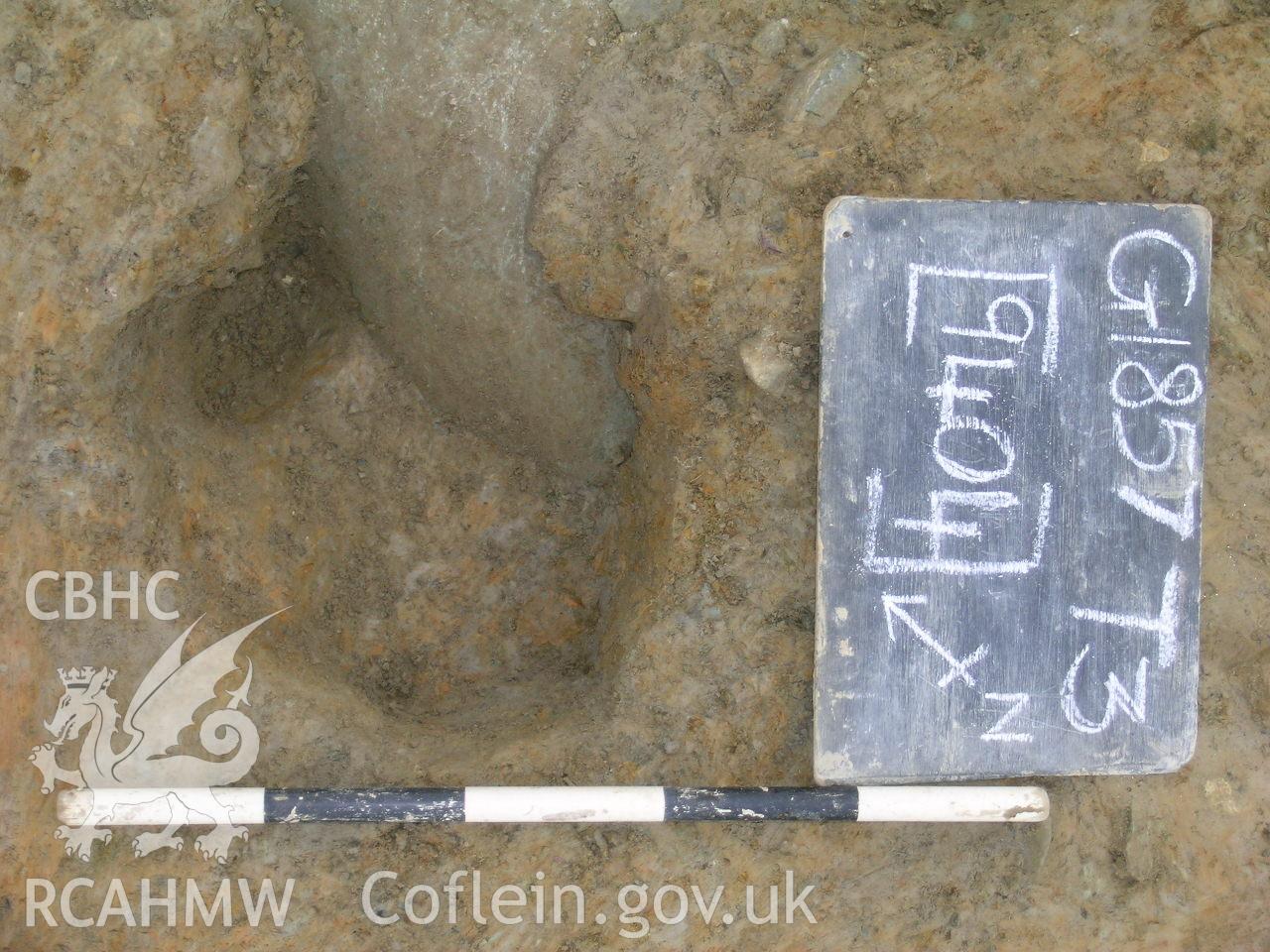 Digital photograph from excavation of Parc Bryn Cegin, Llandygai, by Gwynedd Archaeological Trust. P-ex. Posthole [9404], from E (numbers refer to context records). Scale 1x0.3m.