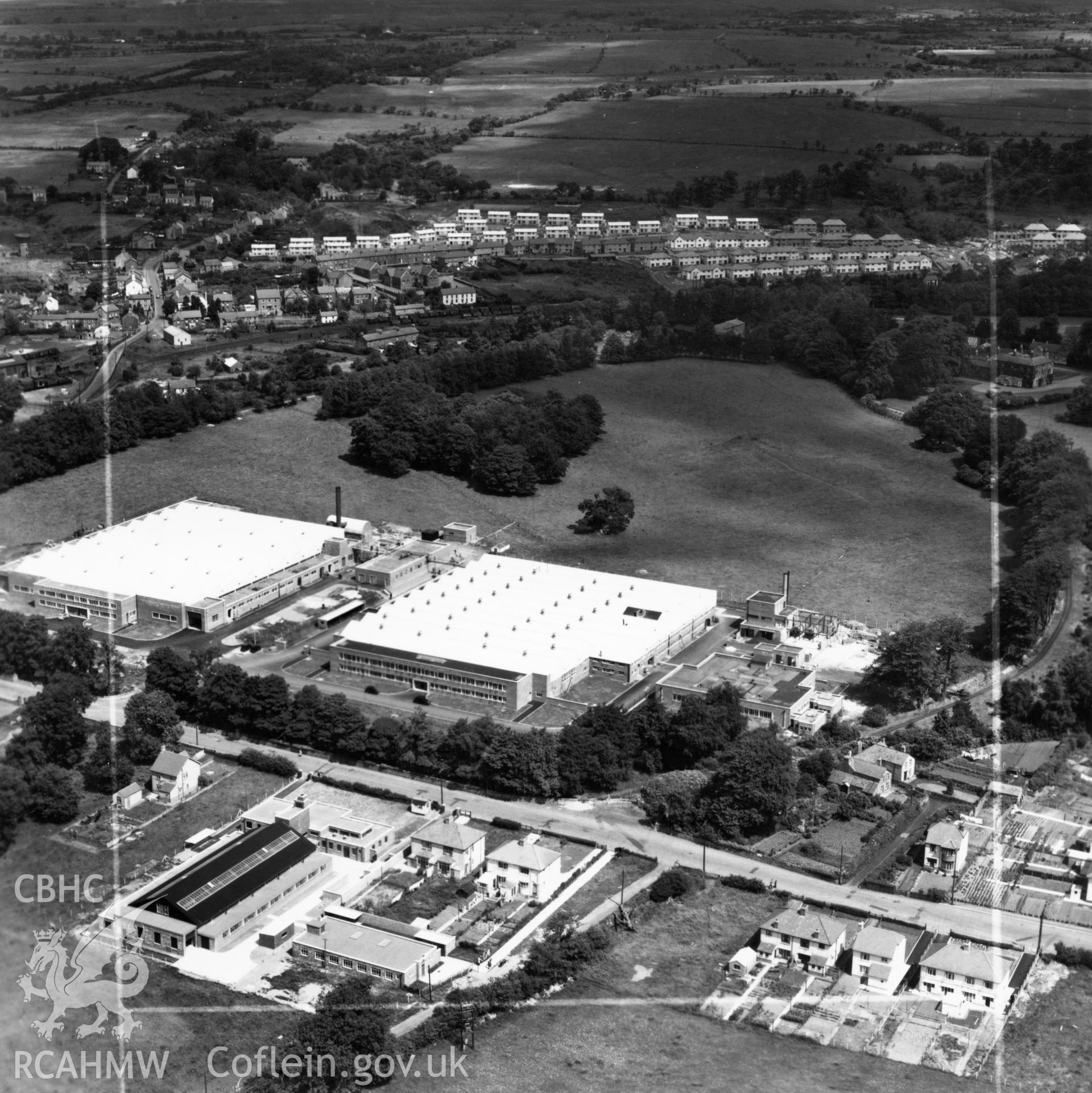 View of Smith's Clock and the Anglo-Welsh watch factories, Gurnos, showing new housing in the distance (commissioned by William Cowlin & Son Ltd.). Oblique aerial photograph, 5?" cut roll film.