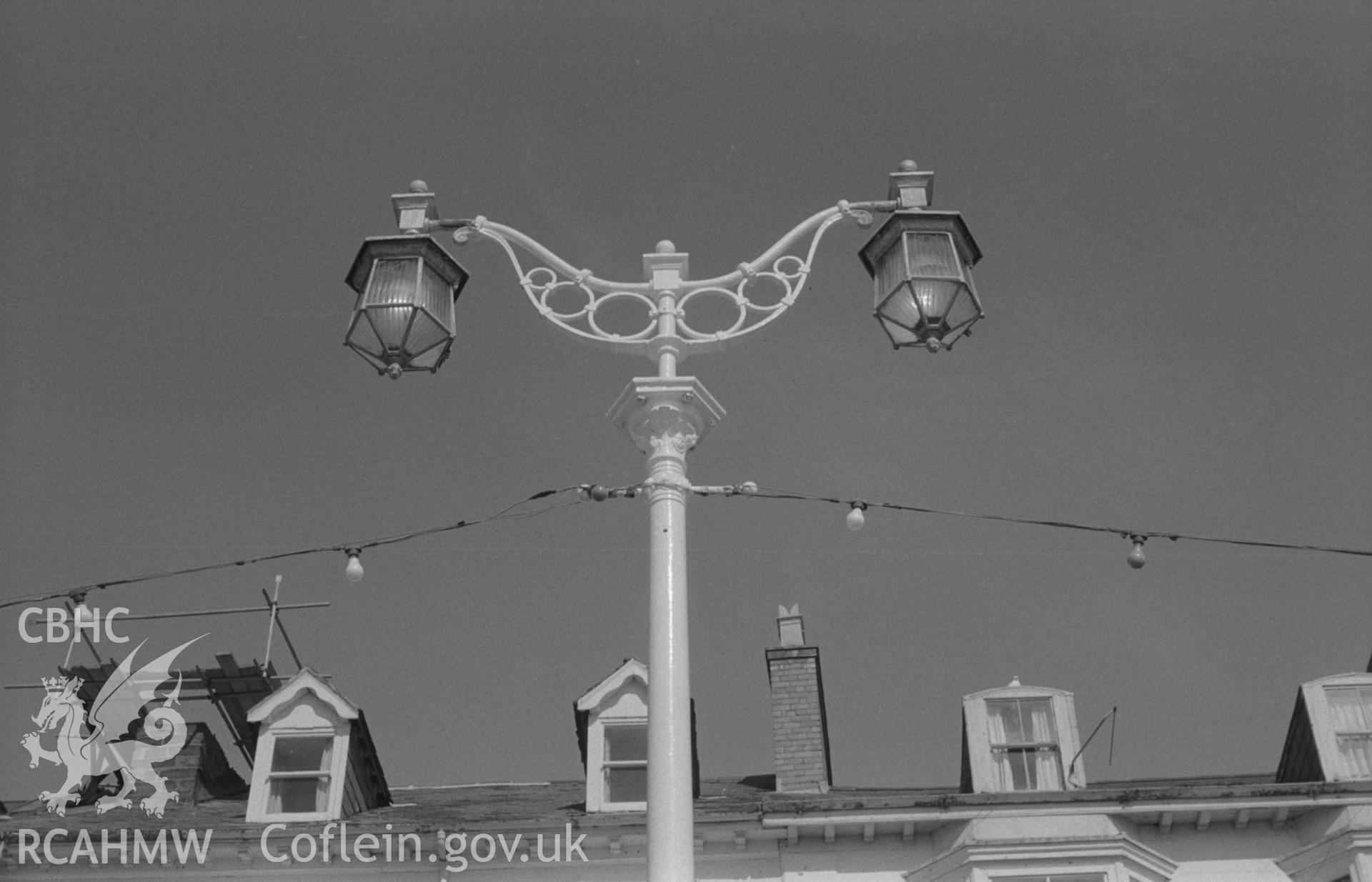 Digital copy of a black and white negative showing lamp post on Aberystwyth promenade near public shelter (opposite Marine hotel). Photographed by Arthur O. Chater in August 1967 looking east from Grid Reference SN 583 821.